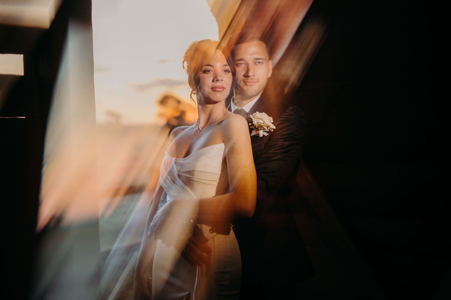 Artistic wedding portrait with soft golden light and dreamy motion blur effects during sunset.