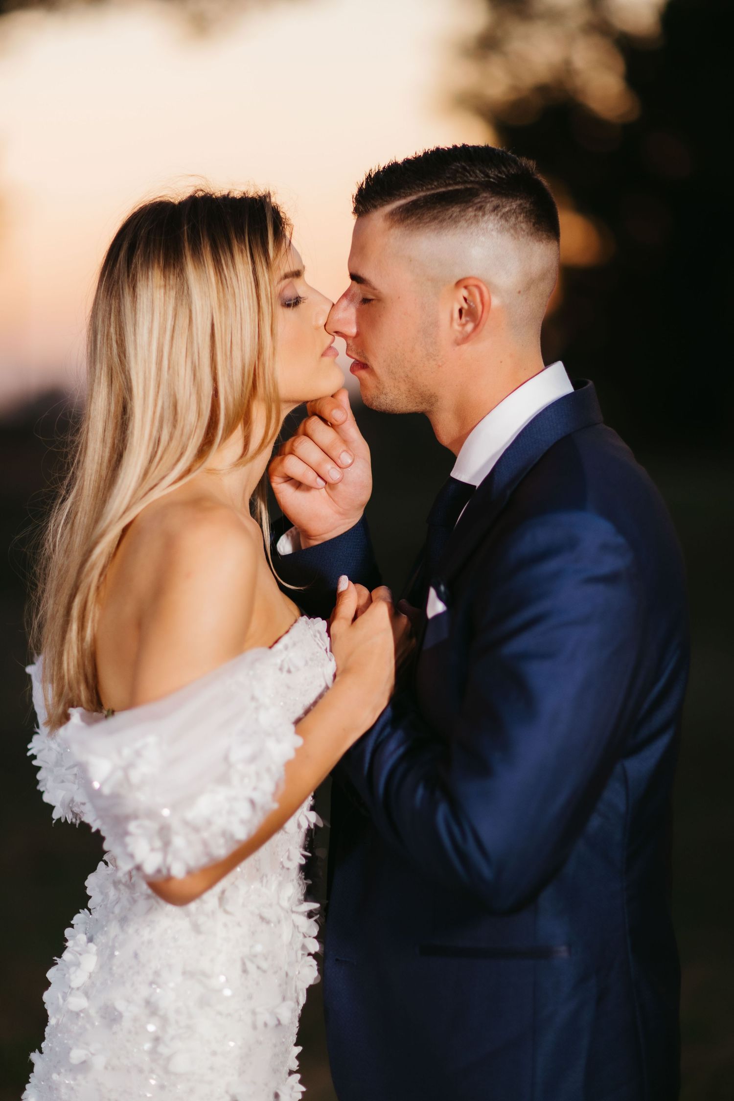 Romantic sunset moment between wedding couple in elegant attire.