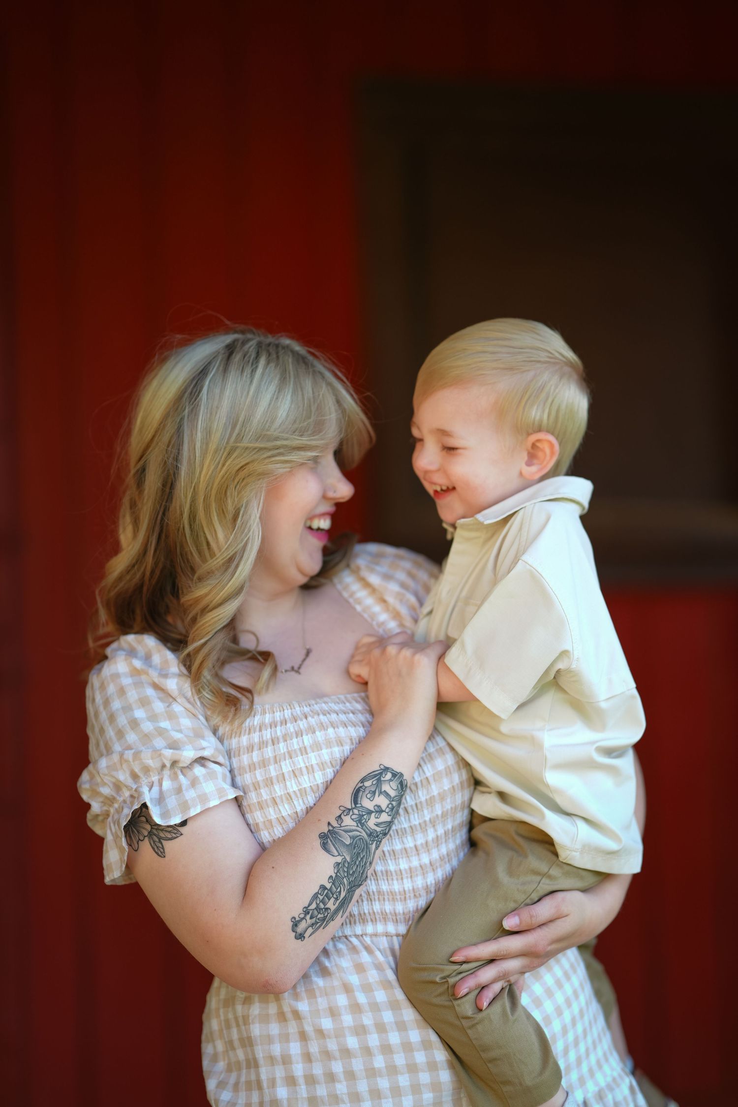 Intimate indoor family portrait against a red background shows loving embrace.
