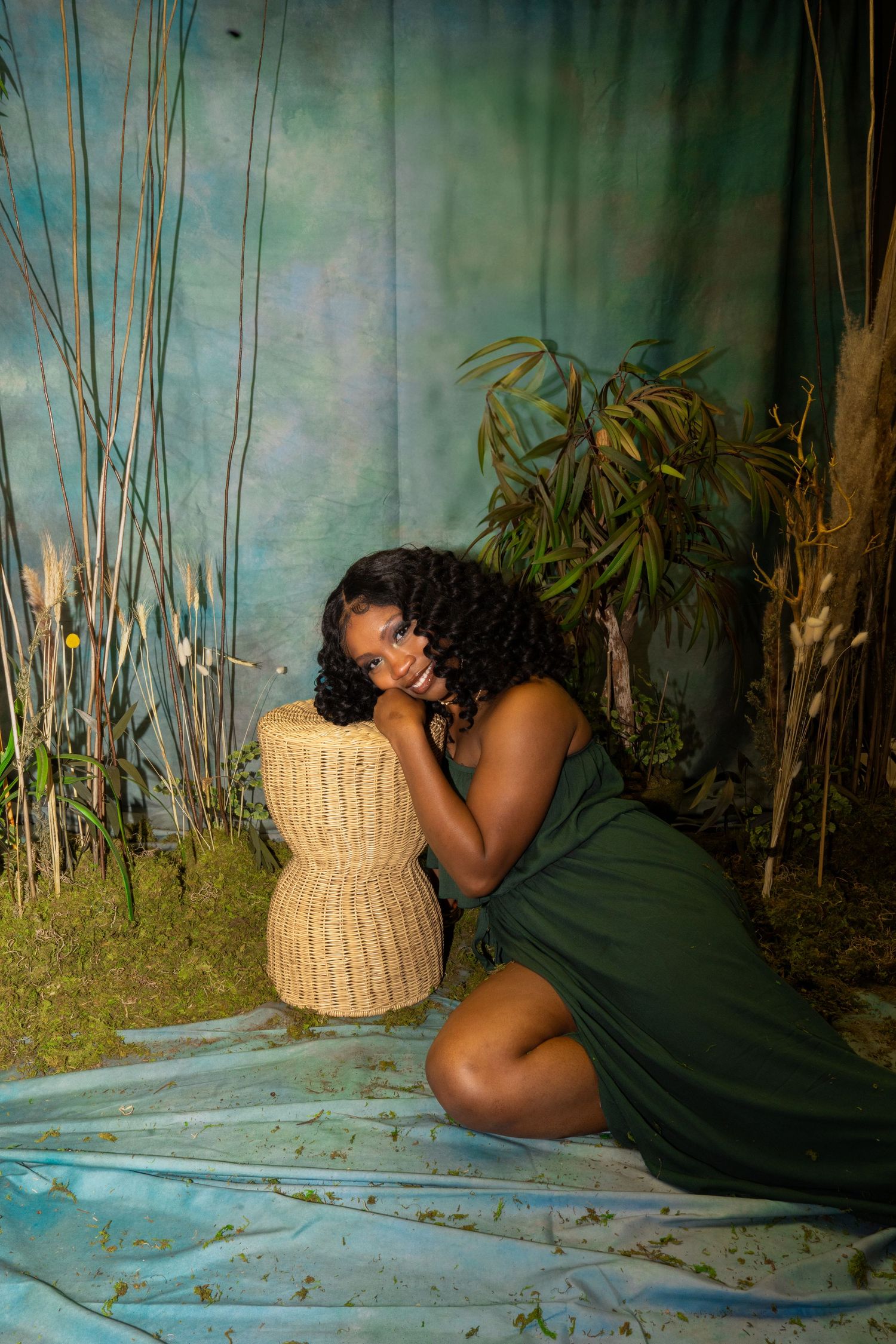 Artistic portrait in moody garden setting with woven decor and flowing dress.