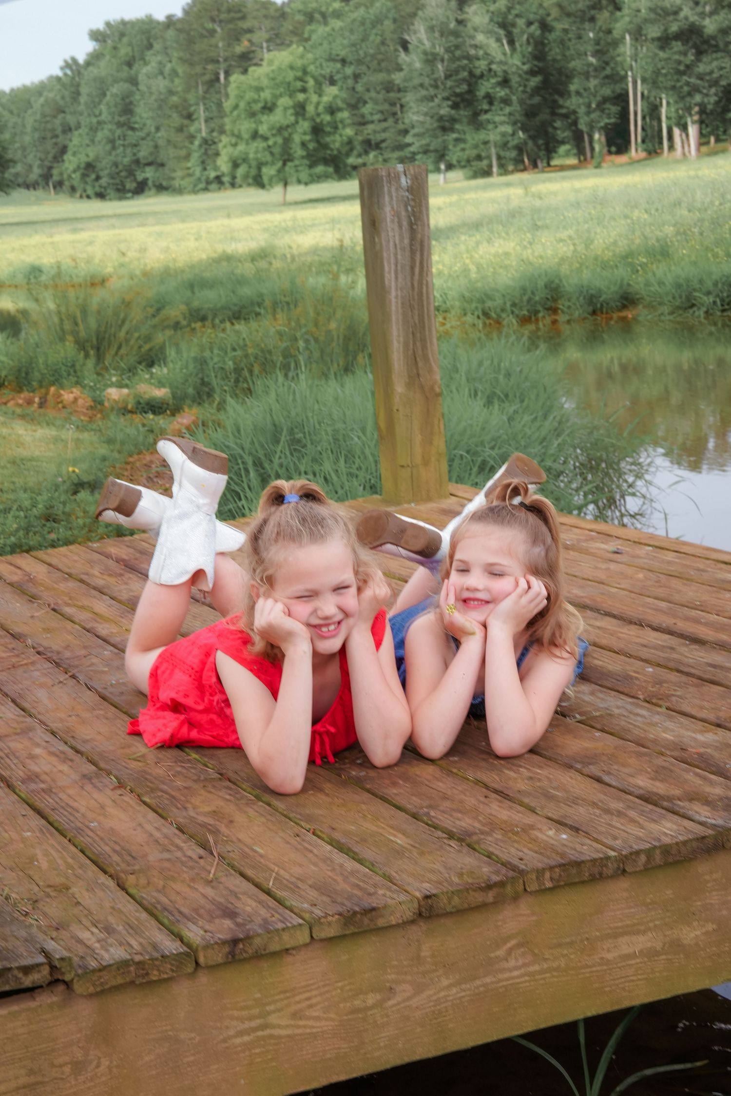 Two people lying on wooden dock wearing red and blue while posing playfully.