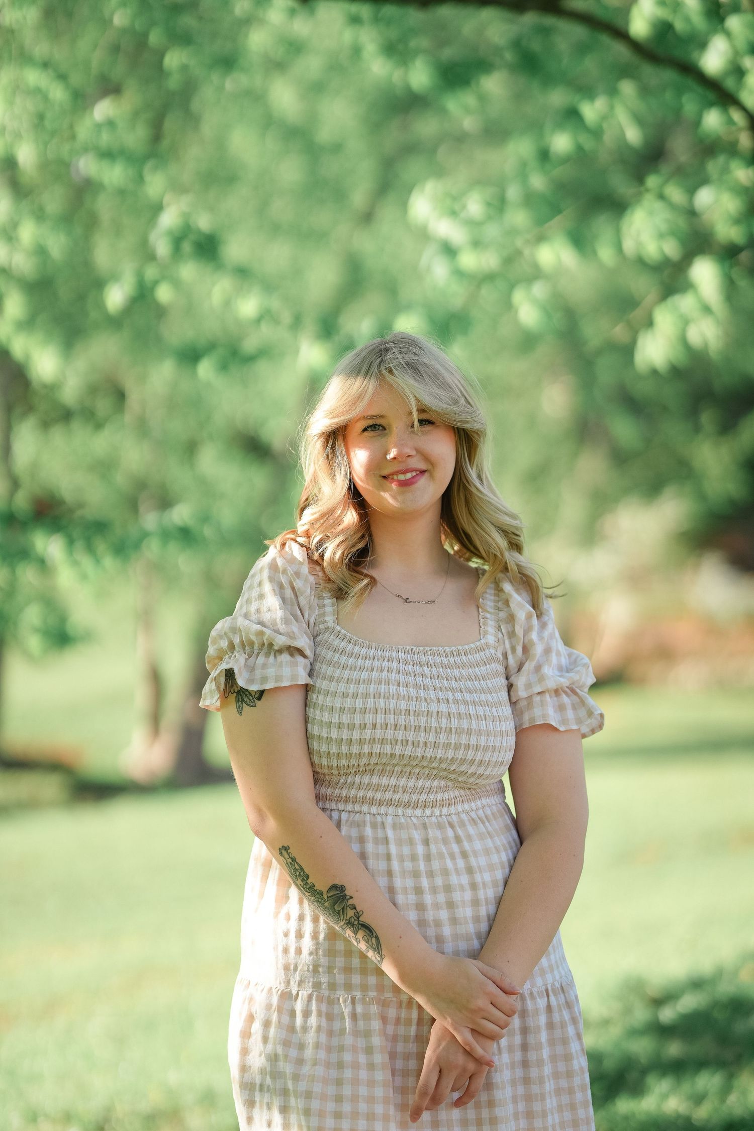 Sunlit garden portrait with person wearing gingham dress with puff sleeves.
