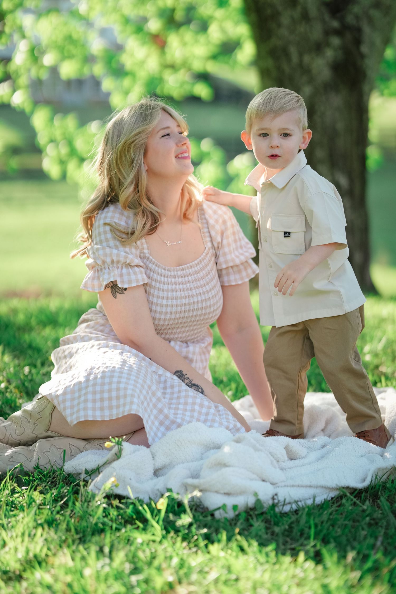 Joyful outdoor family photoshoot captured on white blanket in green park setting.
