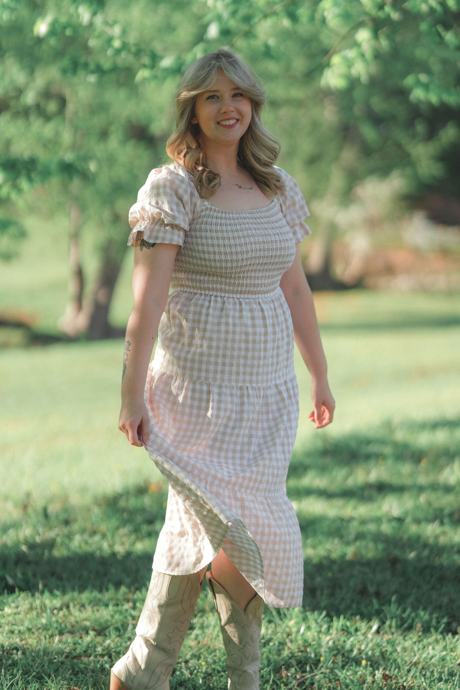 Person wearing a light gingham dress frolics happily in a sunny outdoor setting.