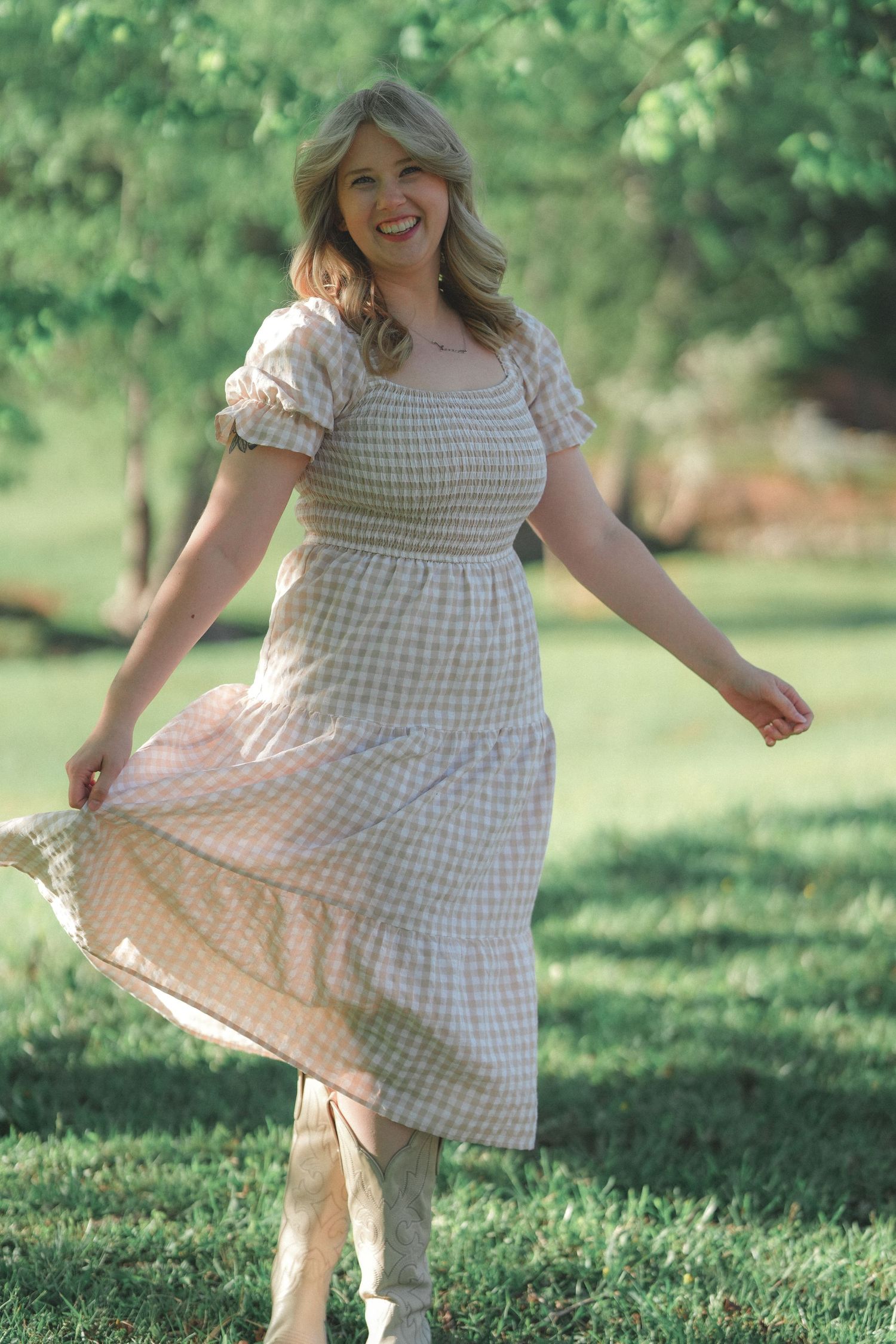 Woman in checkered dress dances and spins gracefully on green grass in a garden.