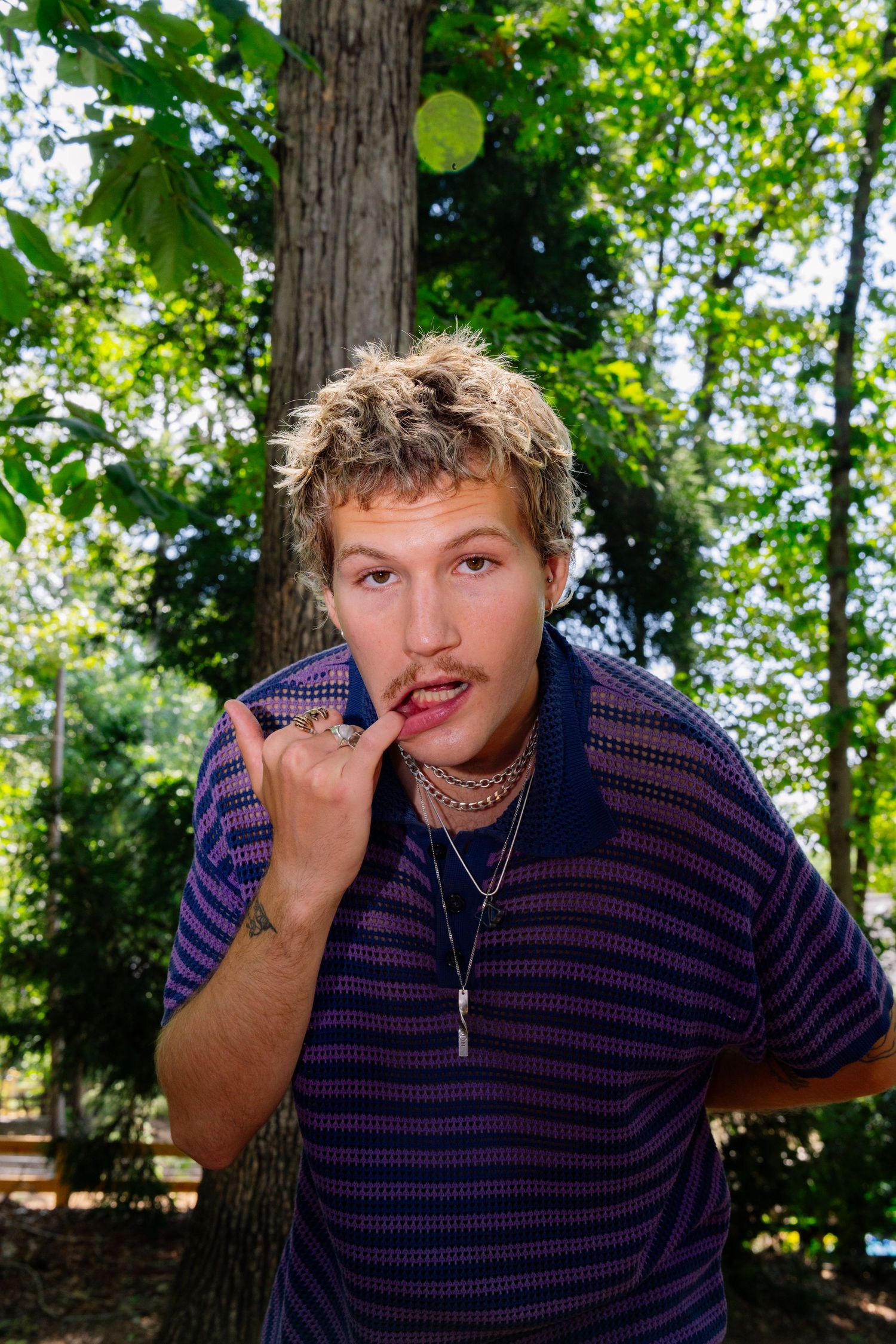 Playful outdoor portrait with person gesturing against forest background.