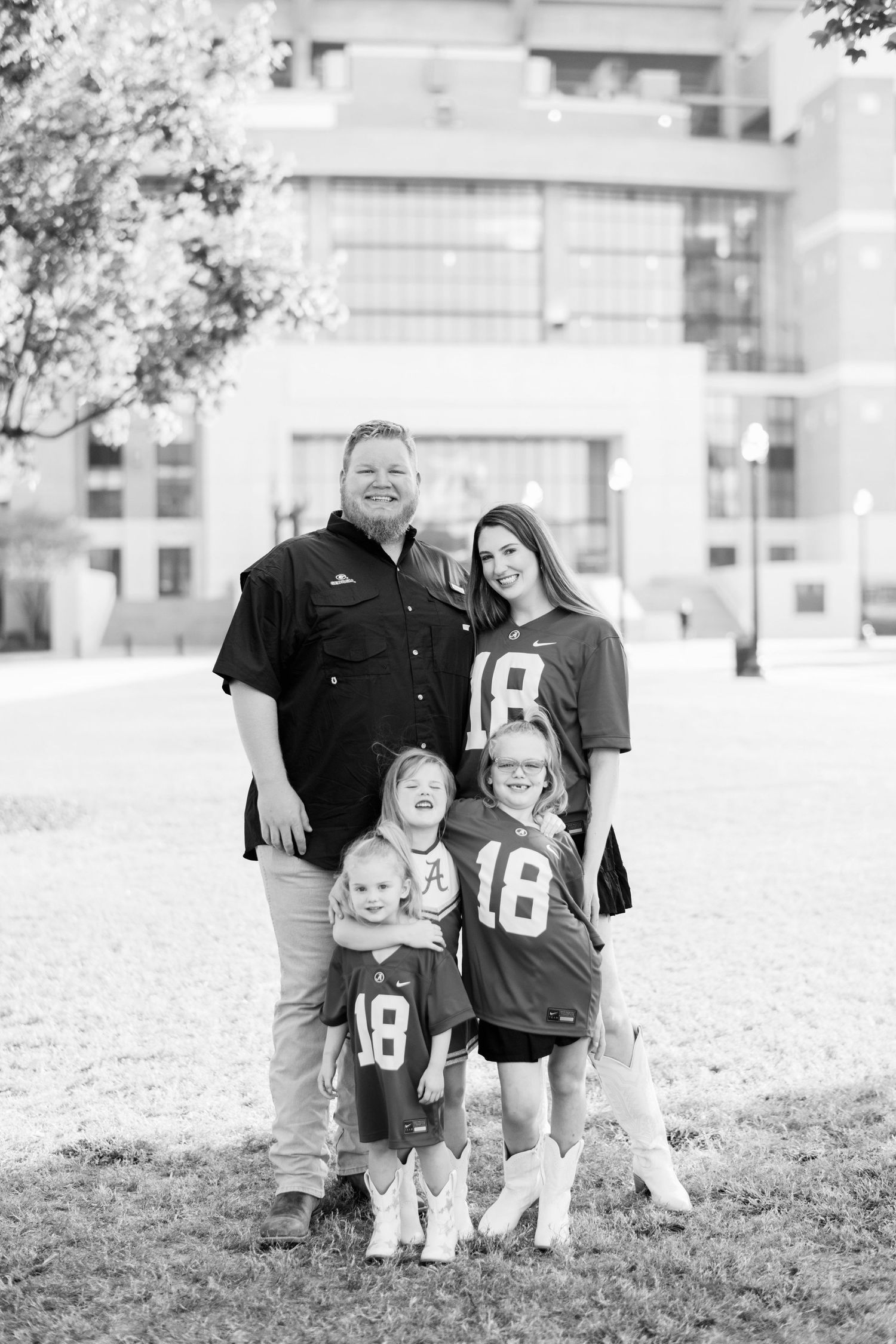 Family wearing matching jerseys poses for portrait outside building.