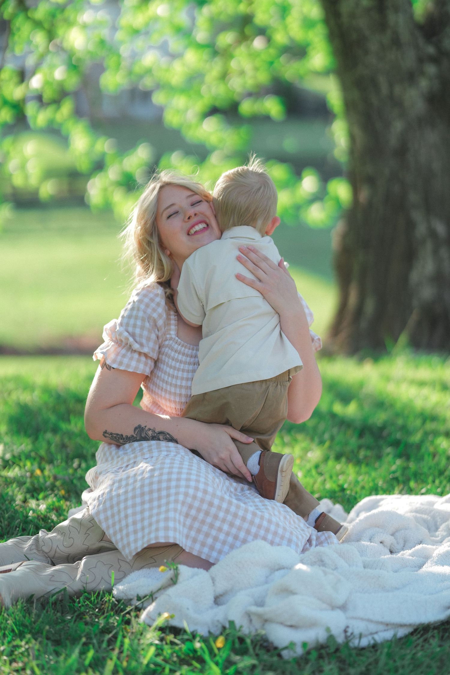 Heartwarming family moment captured on white blanket in sunny park setting.