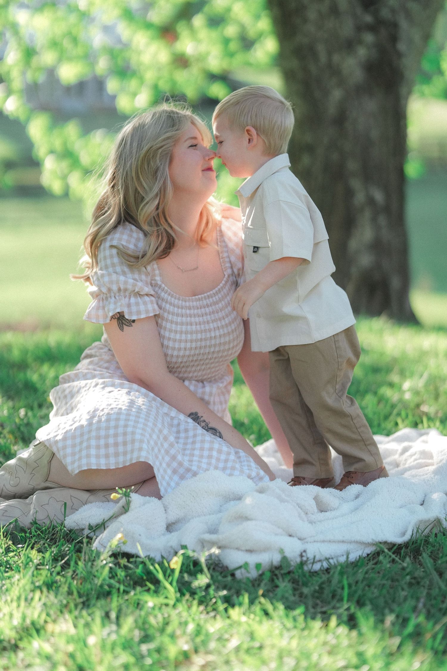 A tender outdoor portrait featuring gingham dress and khaki pants against a sunlit garden background.