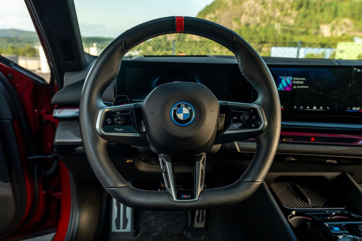 BMW steering wheel with M Sport badge and digital instrument cluster.