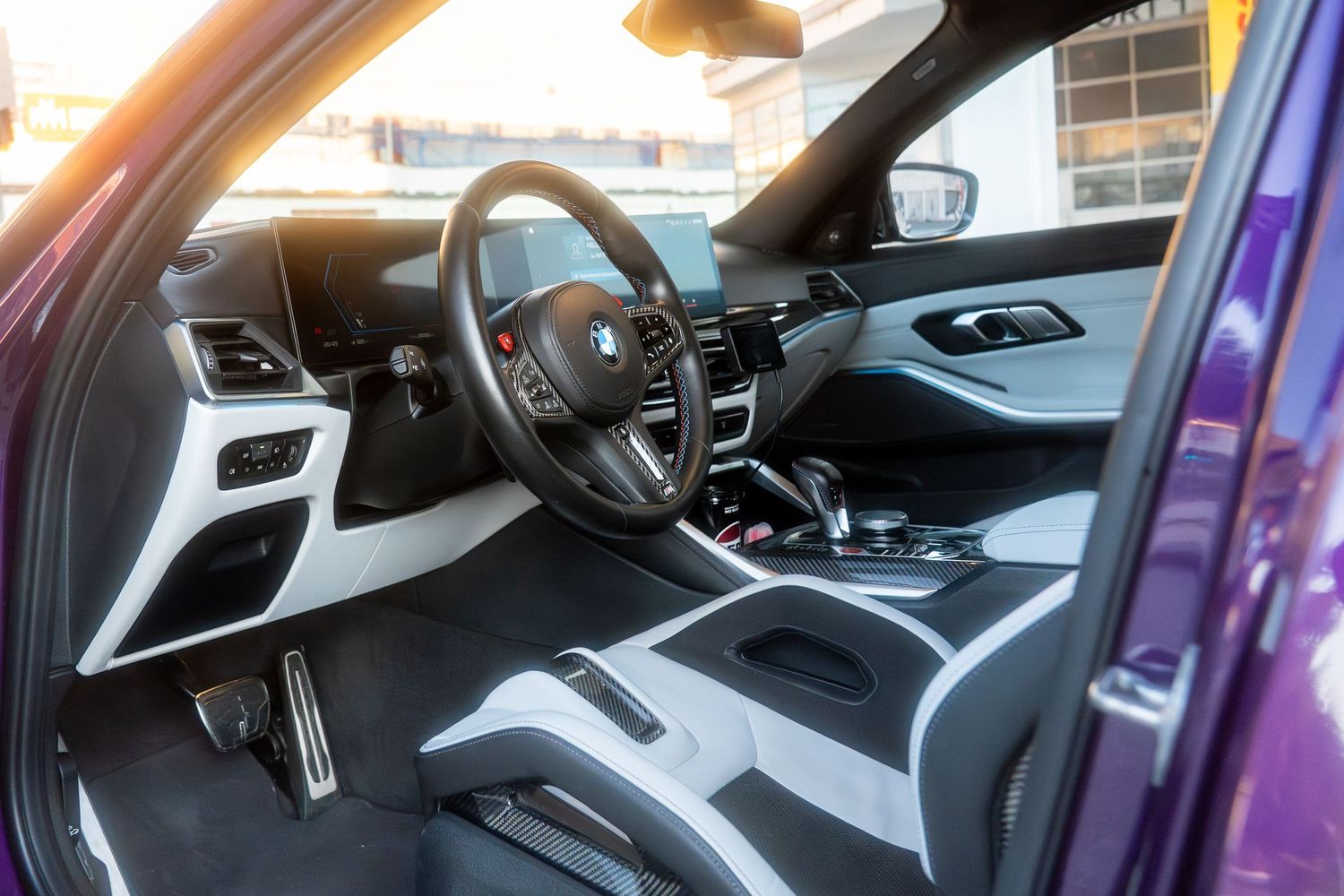 Interior view of a modern BMW luxury car showing black and white dashboard, steering wheel and front seats.