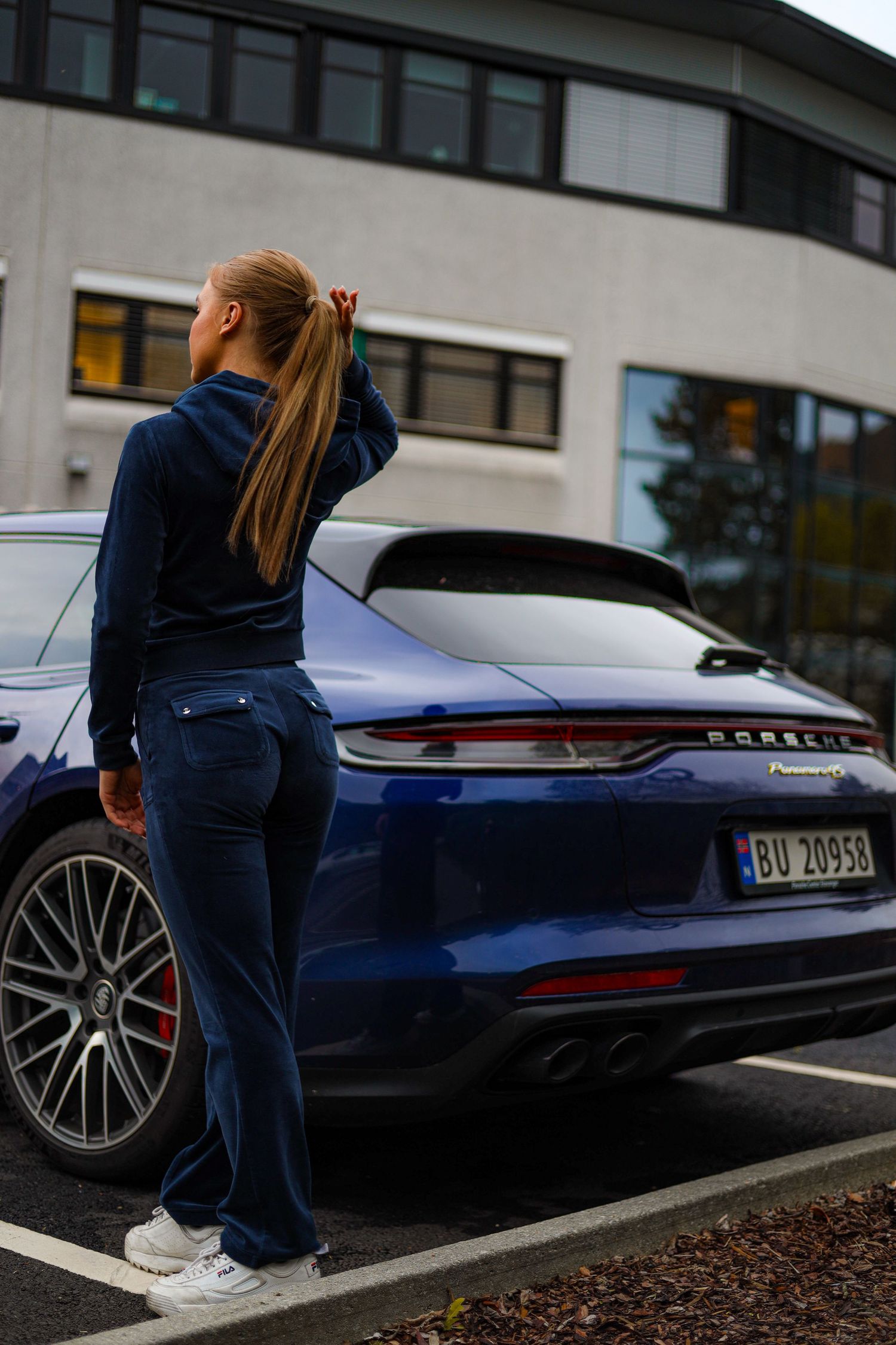 Blue Porsche Panamera Sport Turismo parked in a lot with modern building backdrop.