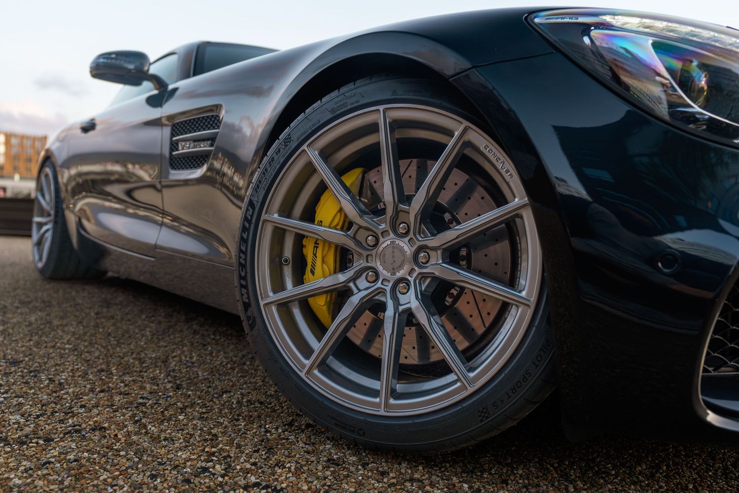 Close-up of Mercedes AMG GT wheel with yellow brake caliper and detailed rim design.