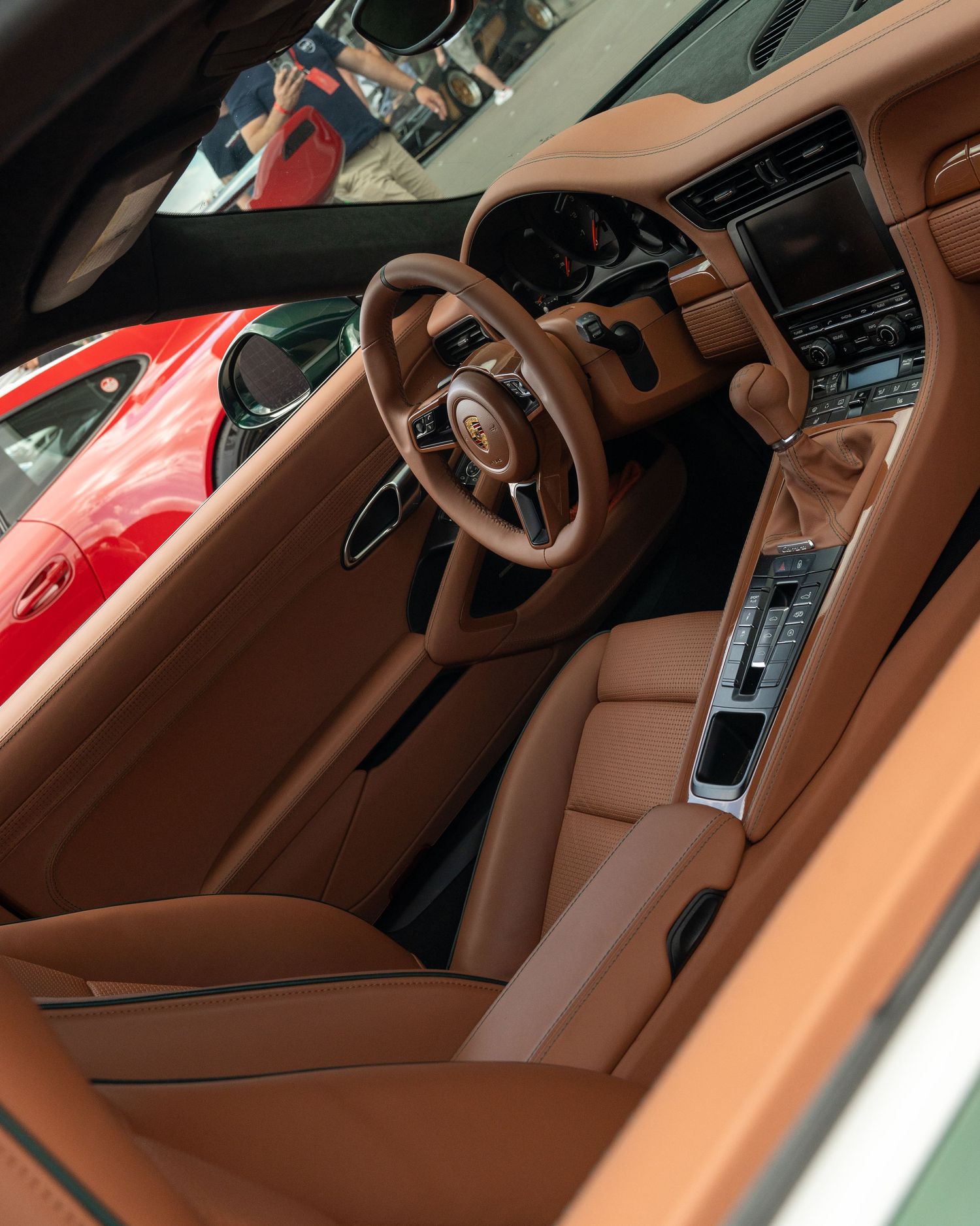 Luxurious brown leather interior of a modern sports car showing steering wheel and center console.