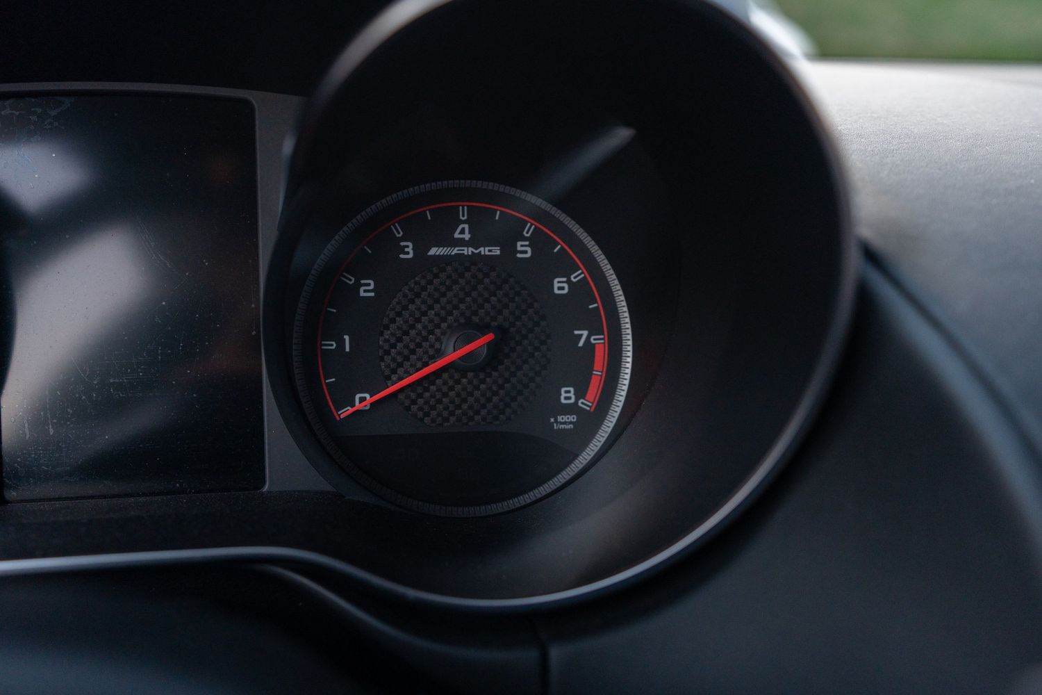 Close-up of a modern car's tachometer gauge showing red needle against black instrument cluster.