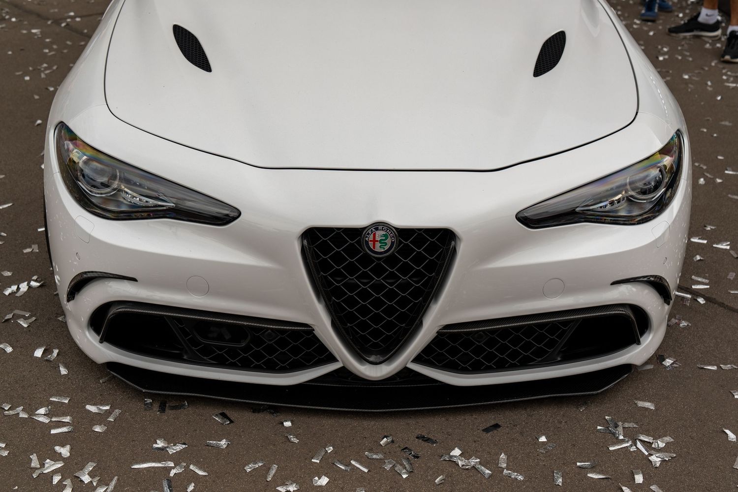 Front view of white Alfa Romeo Giulia showing aggressive grille and hood design.