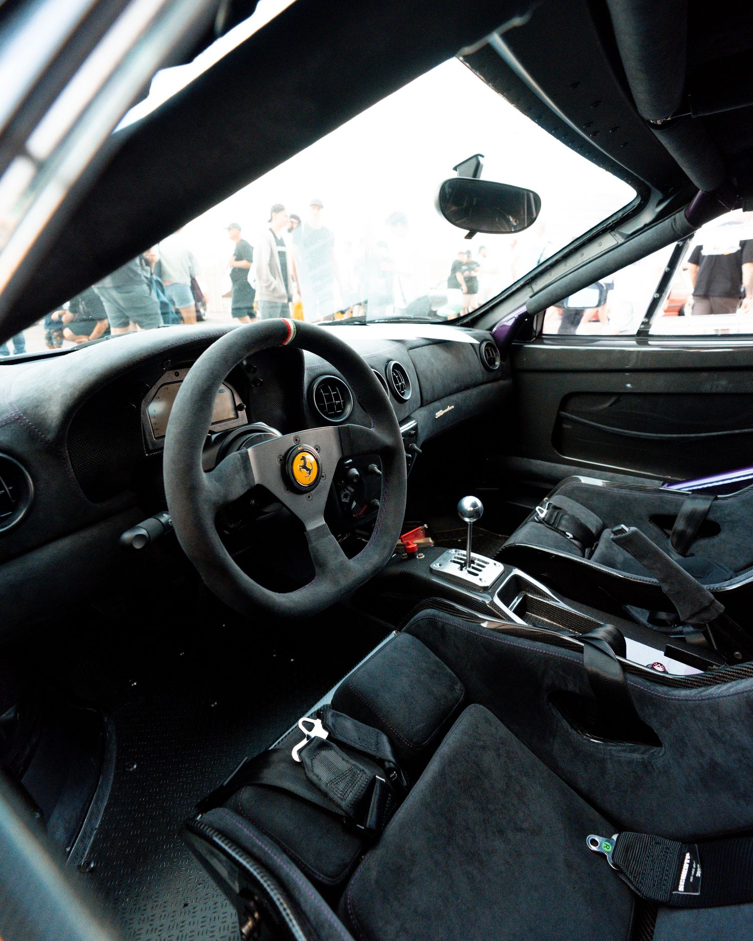 Interior view of a performance car showing racing seats and steering wheel in dark carbon fiber trim.