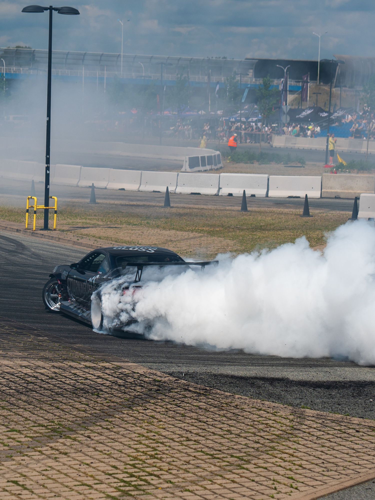 High-performance car performing a dramatic burnout on a paved lot with smoke billowing.