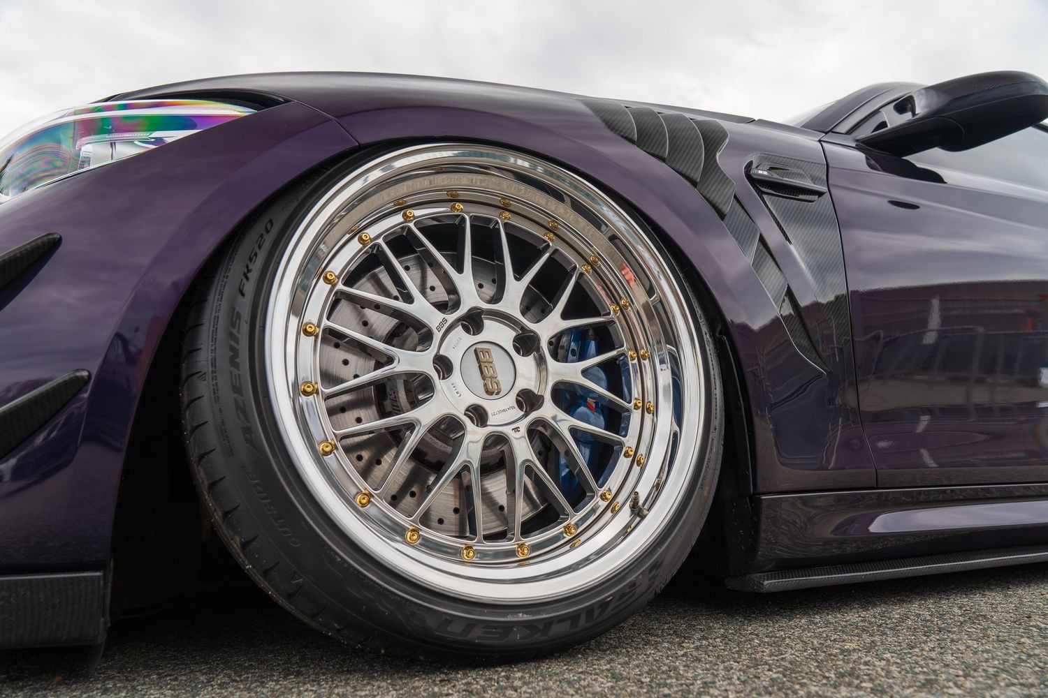 Purple sports car with custom silver multi-spoke wheels and extreme negative camber stance.