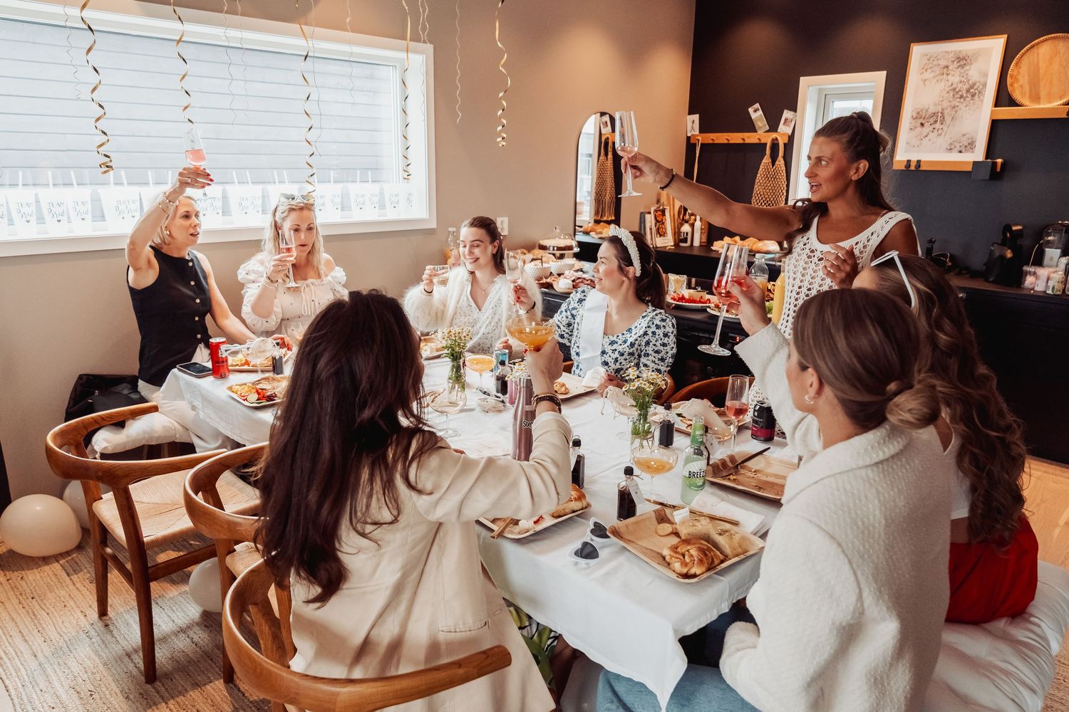 Women gathered around a table enjoying brunch with pastries and drinks.