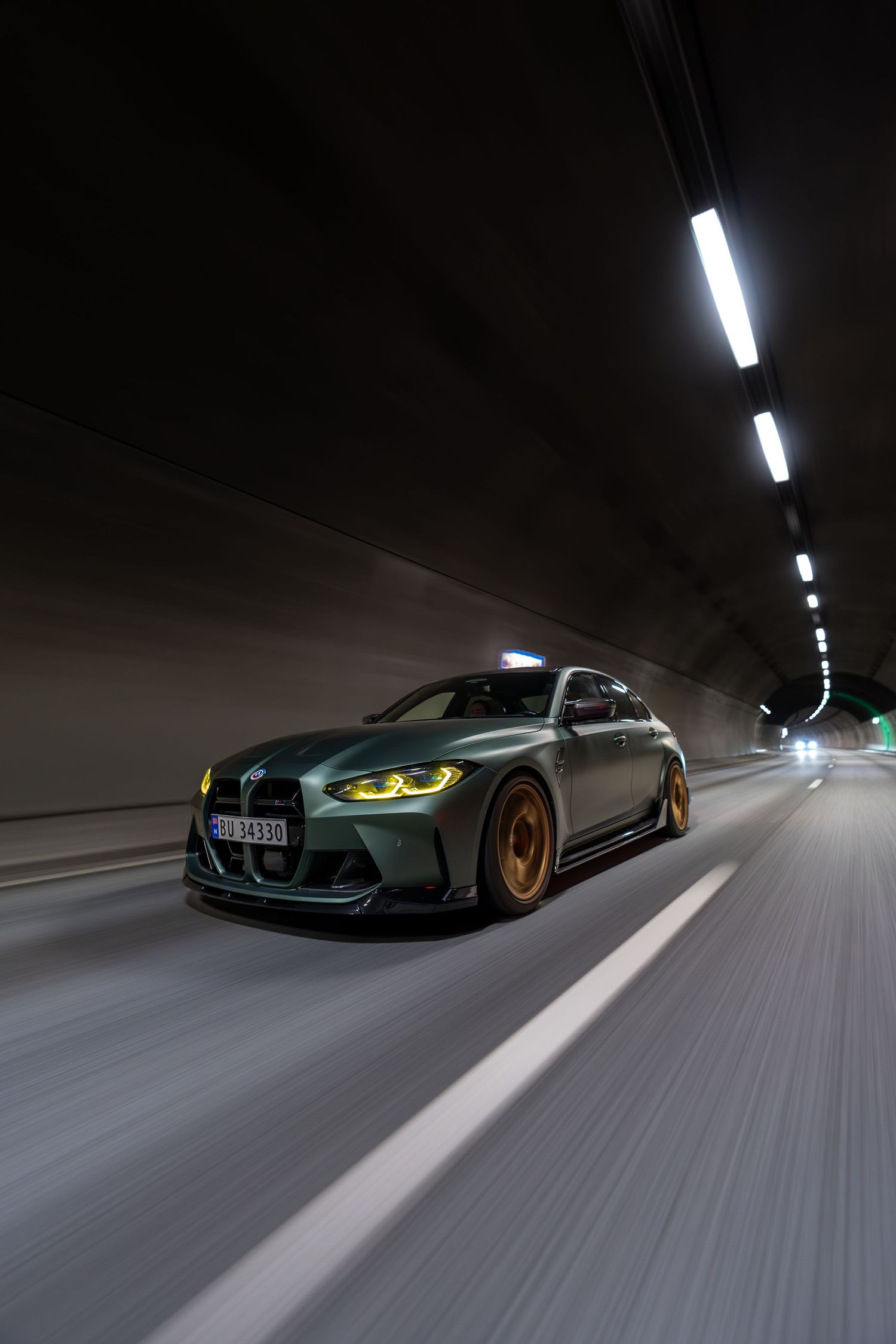 BMW M3 speeding through illuminated tunnel creating dramatic motion blur effect.