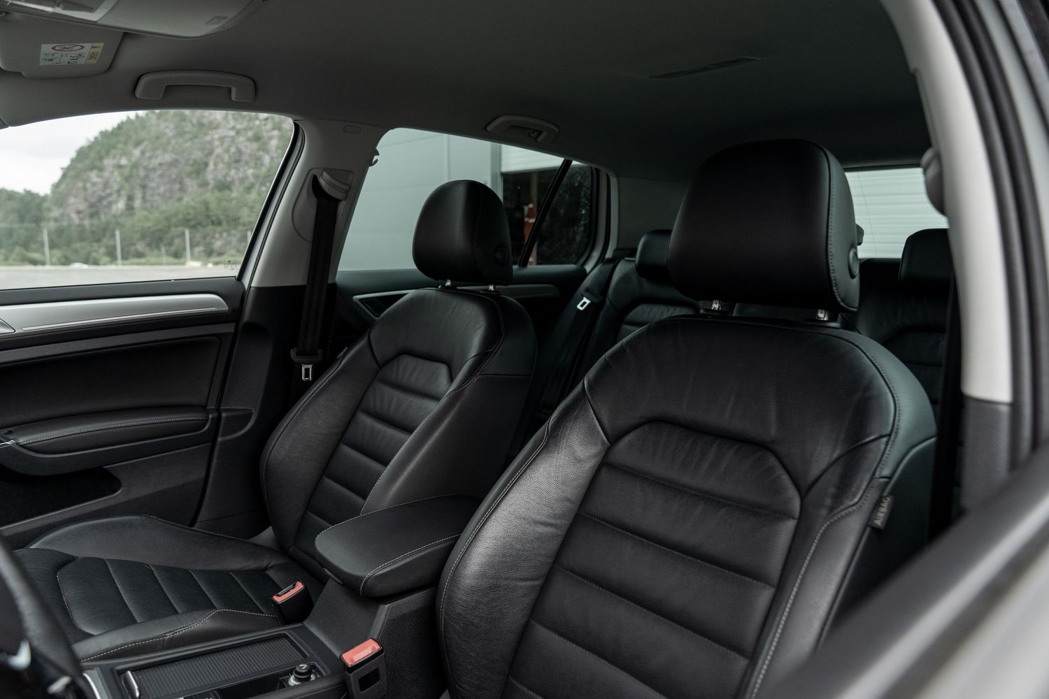 Black leather seats in a luxury car interior showing rear passenger space and door panels.