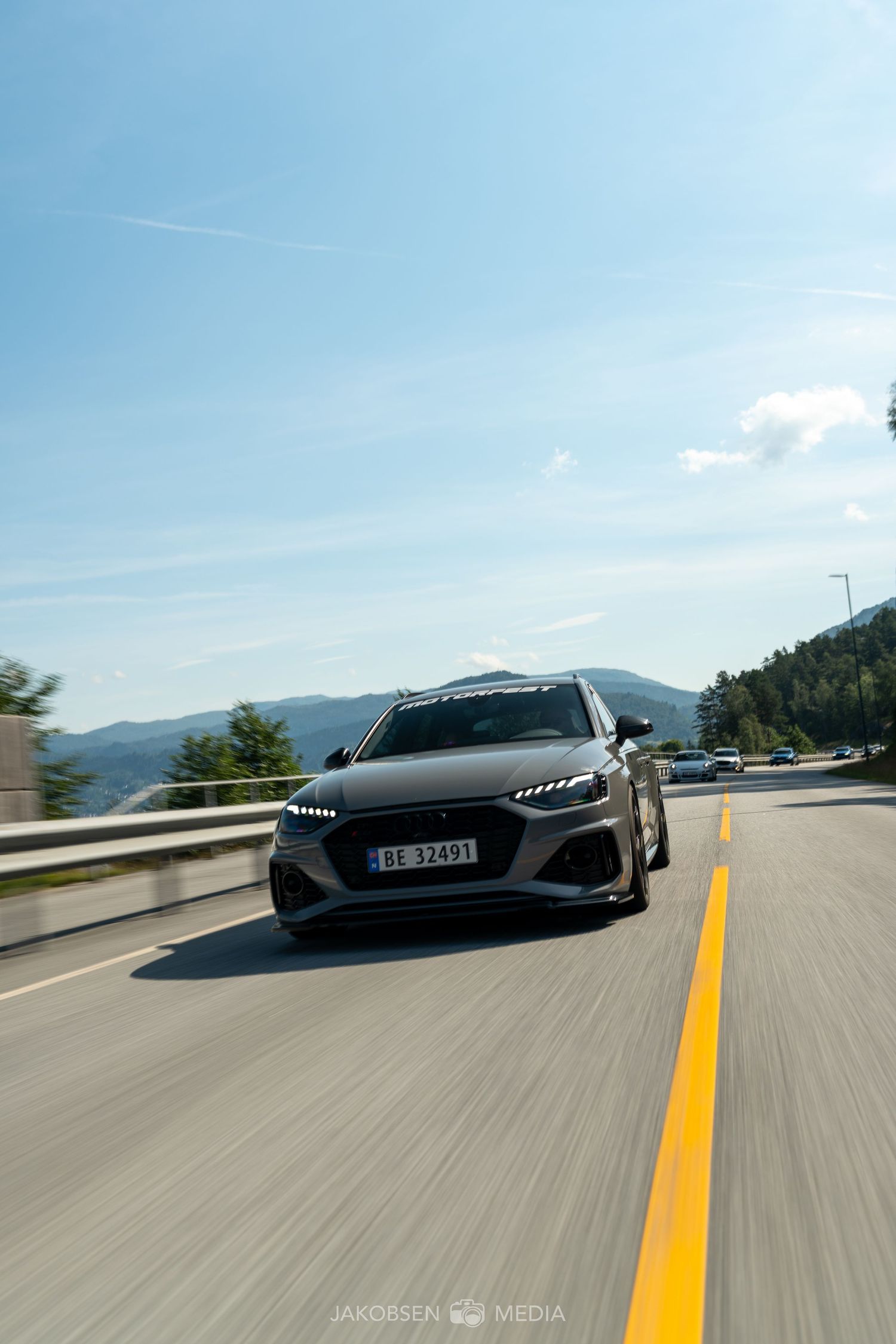 Black Audi R8 supercar driving on a mountain road with yellow lane markings.