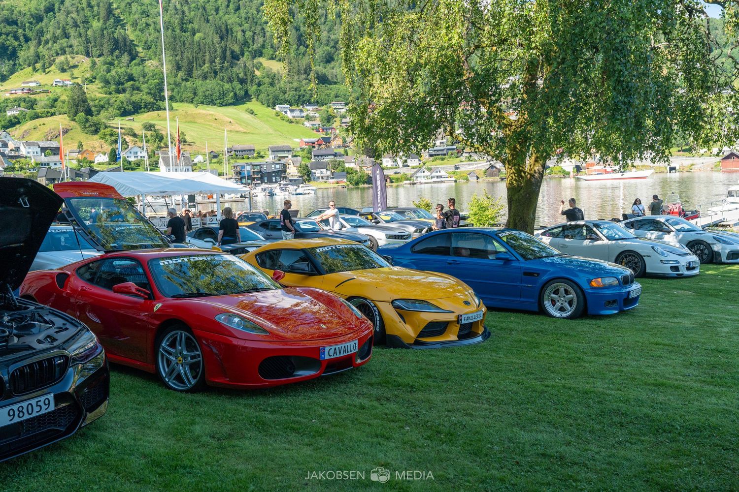 Sports cars lined up on a lawn for a car show display.