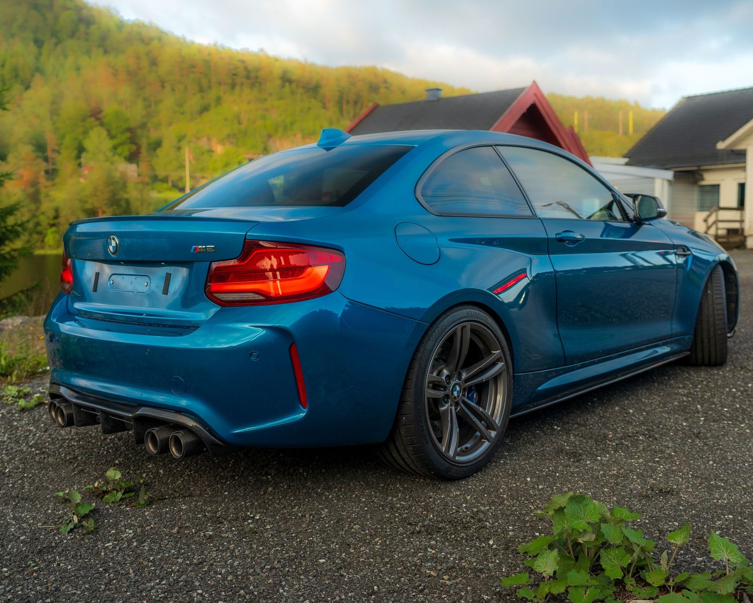 Modified BMW M4 in metallic blue photographed against natural landscape.