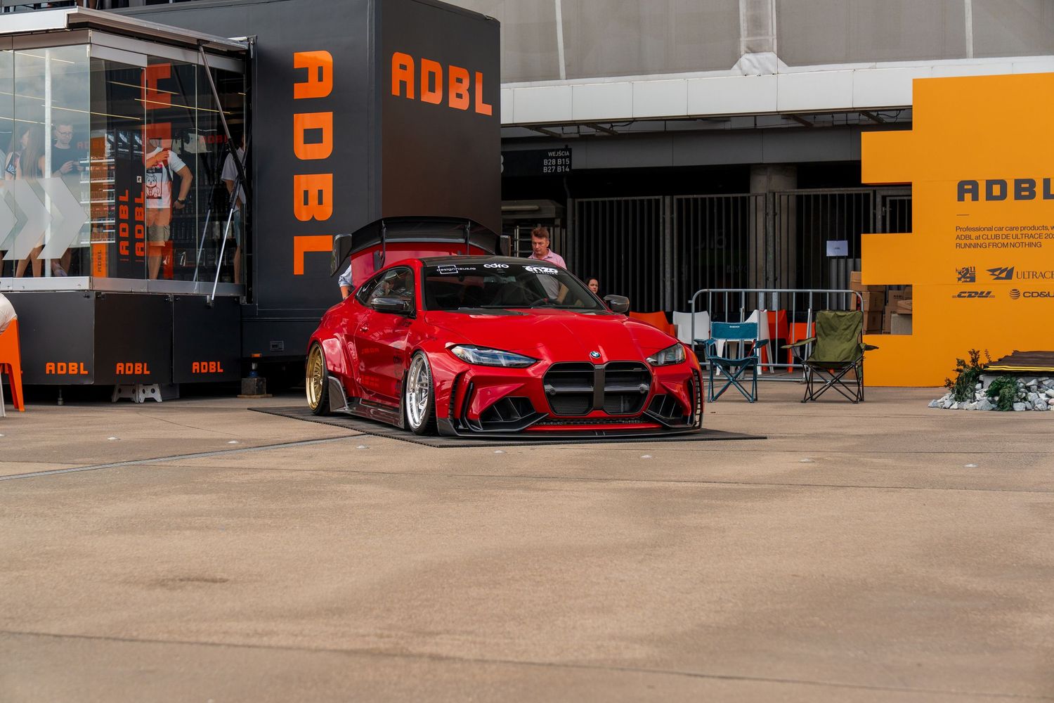 Red modified Mercedes-AMG with lowered suspension and custom bodywork parked outside a shop.