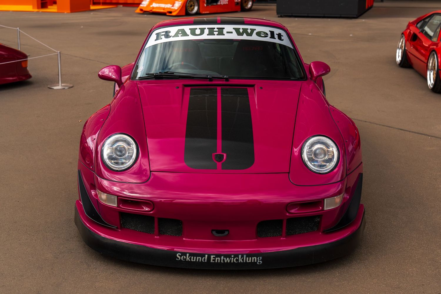 Pink Porsche RWB race car with black racing stripes and custom body kit.