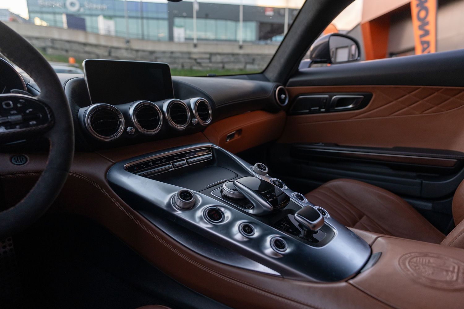 Luxury car center console with gear selector and circular air vents in brown leather interior. bergen