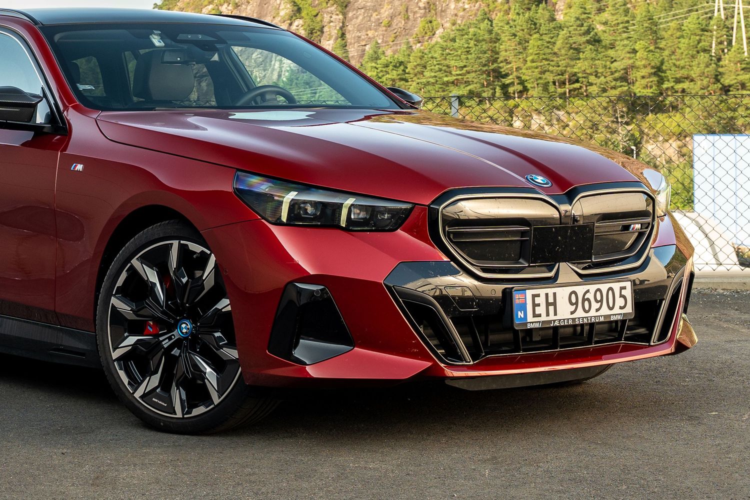 Front view of red BMW showing aggressive M Sport bumper and large kidney grille.