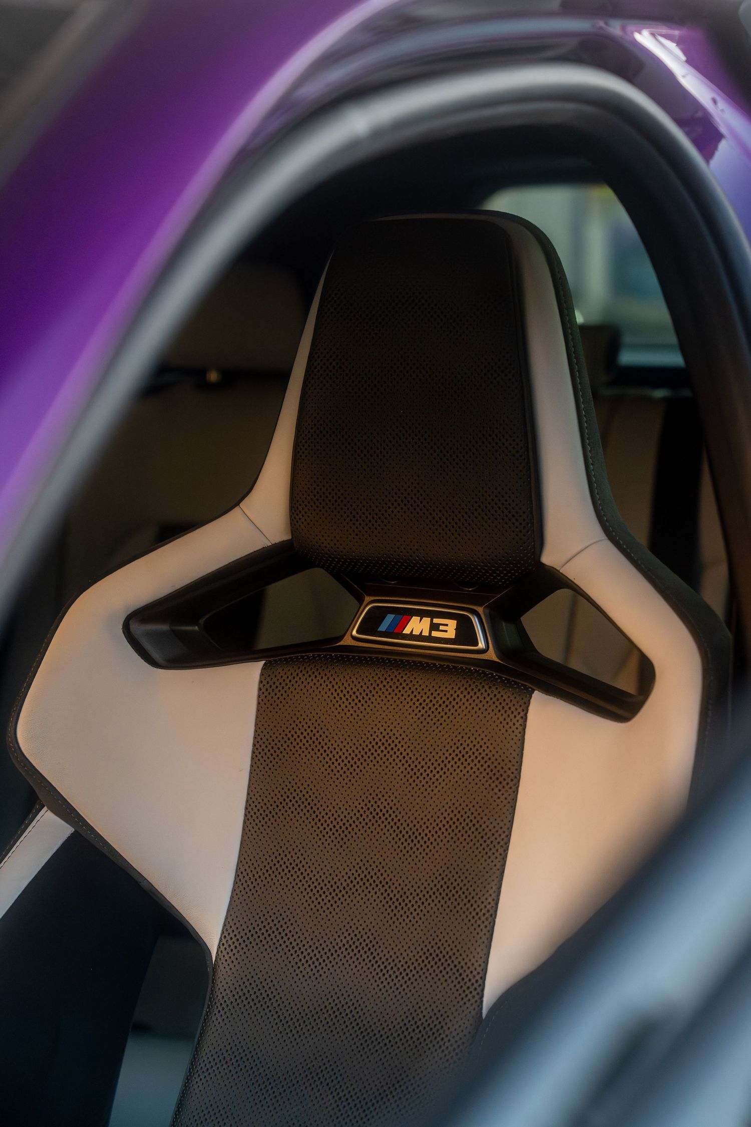 Racing-style seat with white and black upholstery featuring carbon fiber accents viewed from different perspectives.