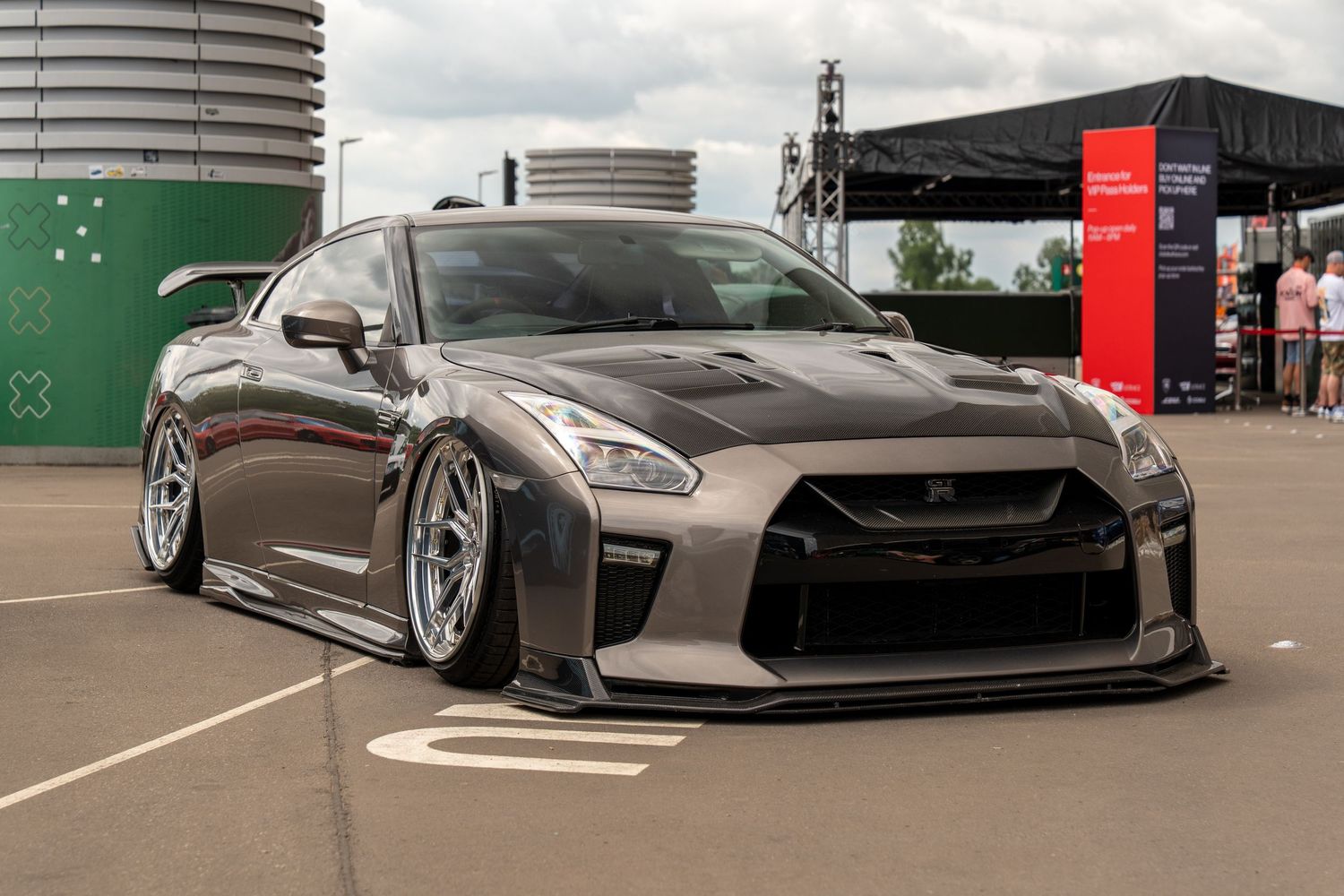 Lowered Nissan GT-R with wide body kit and aggressive stance parked in outdoor event space.