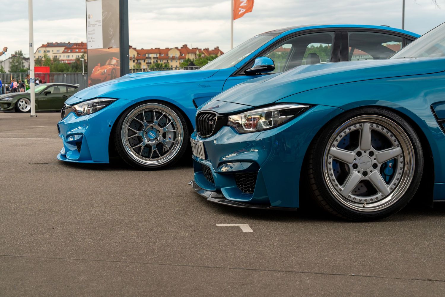 Front view of two modified BMW M3s in bright blue showcasing custom wheels and aggressive stance.