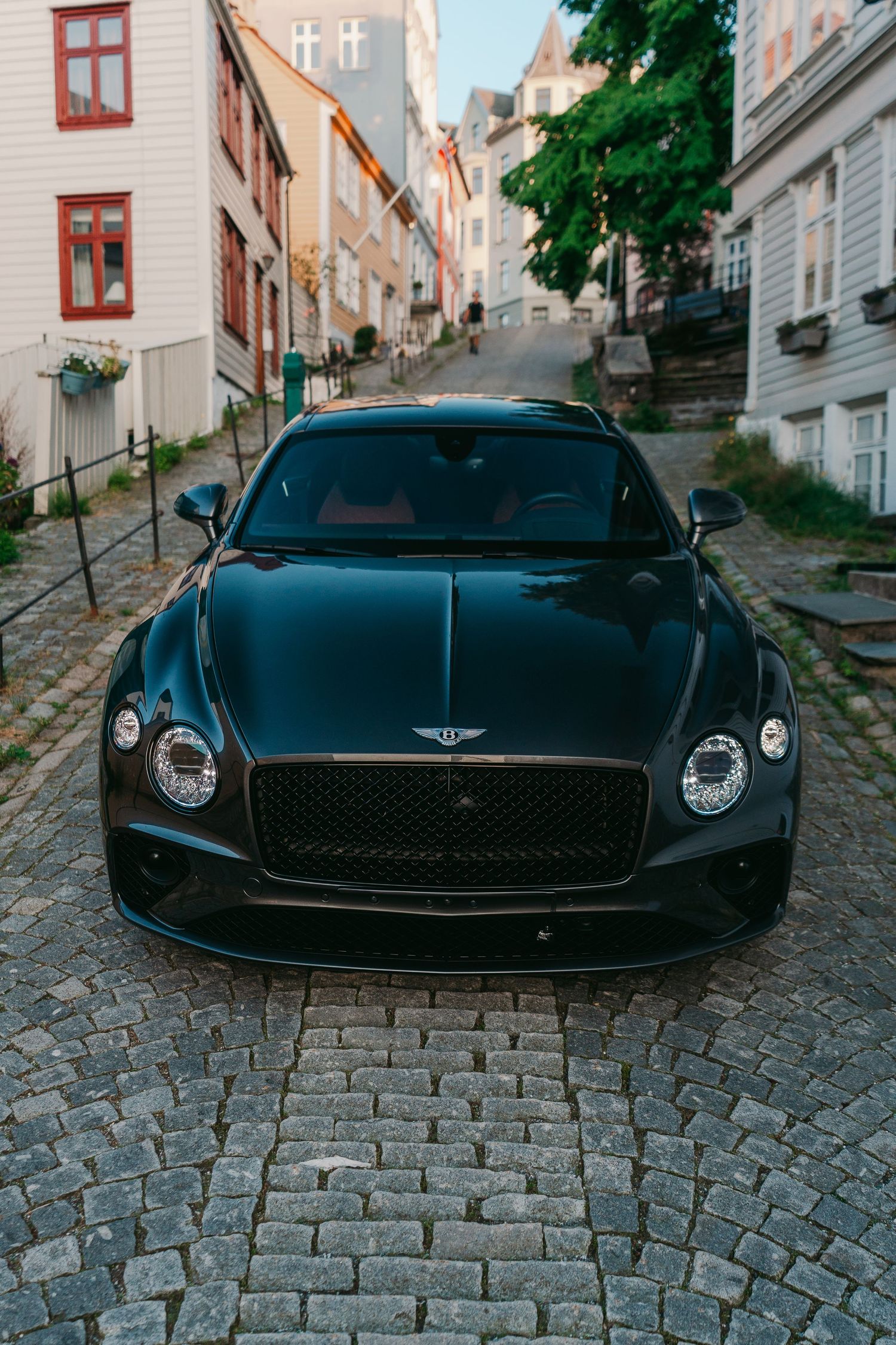 Black Bentley Continental GT parked on a cobblestone street surrounded by traditional European architecture.