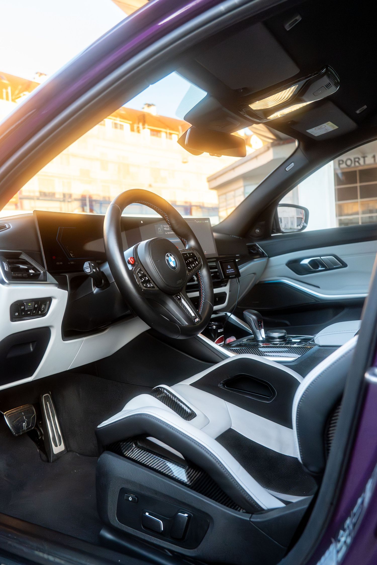 Interior view of a modern BMW vehicle showing sleek black and white dashboard design with digital displays and controls.