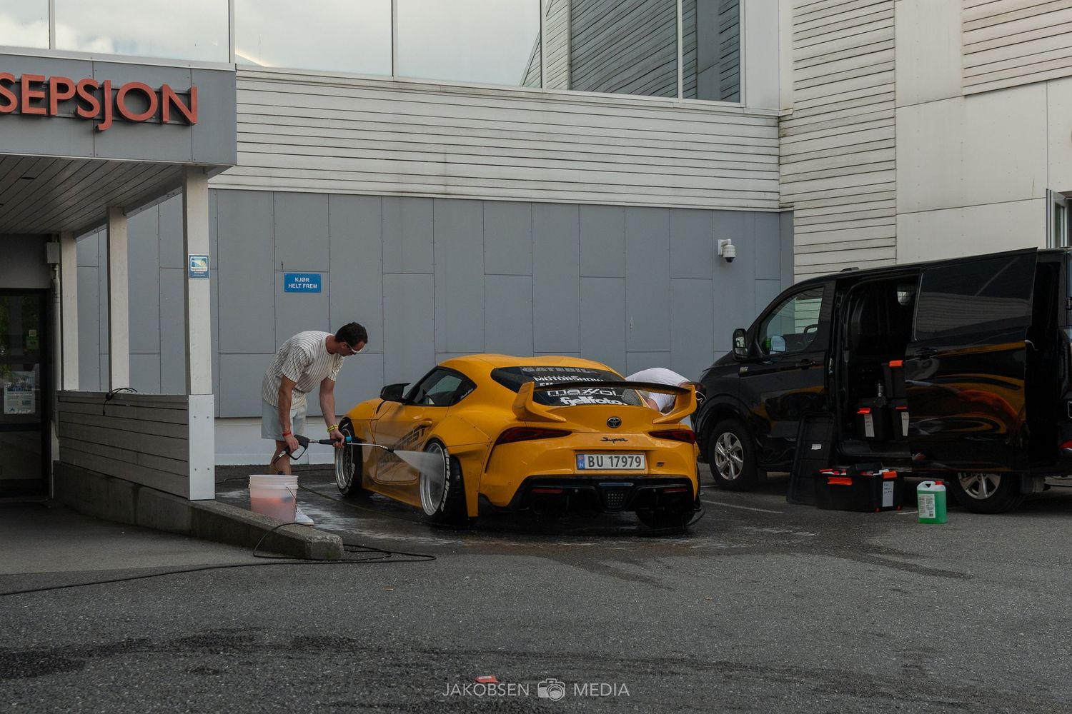 Row of bright orange McLaren supercars parked outside a white industrial building.
