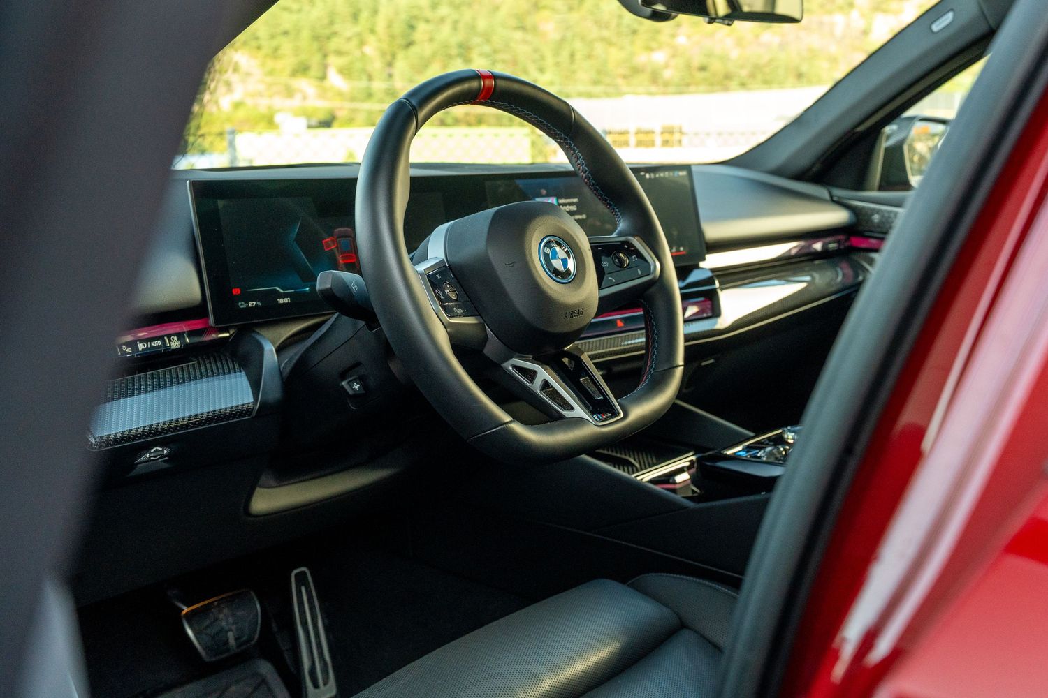 Close-up view of a modern BMW dashboard showing digital displays and red ambient lighting interior.
