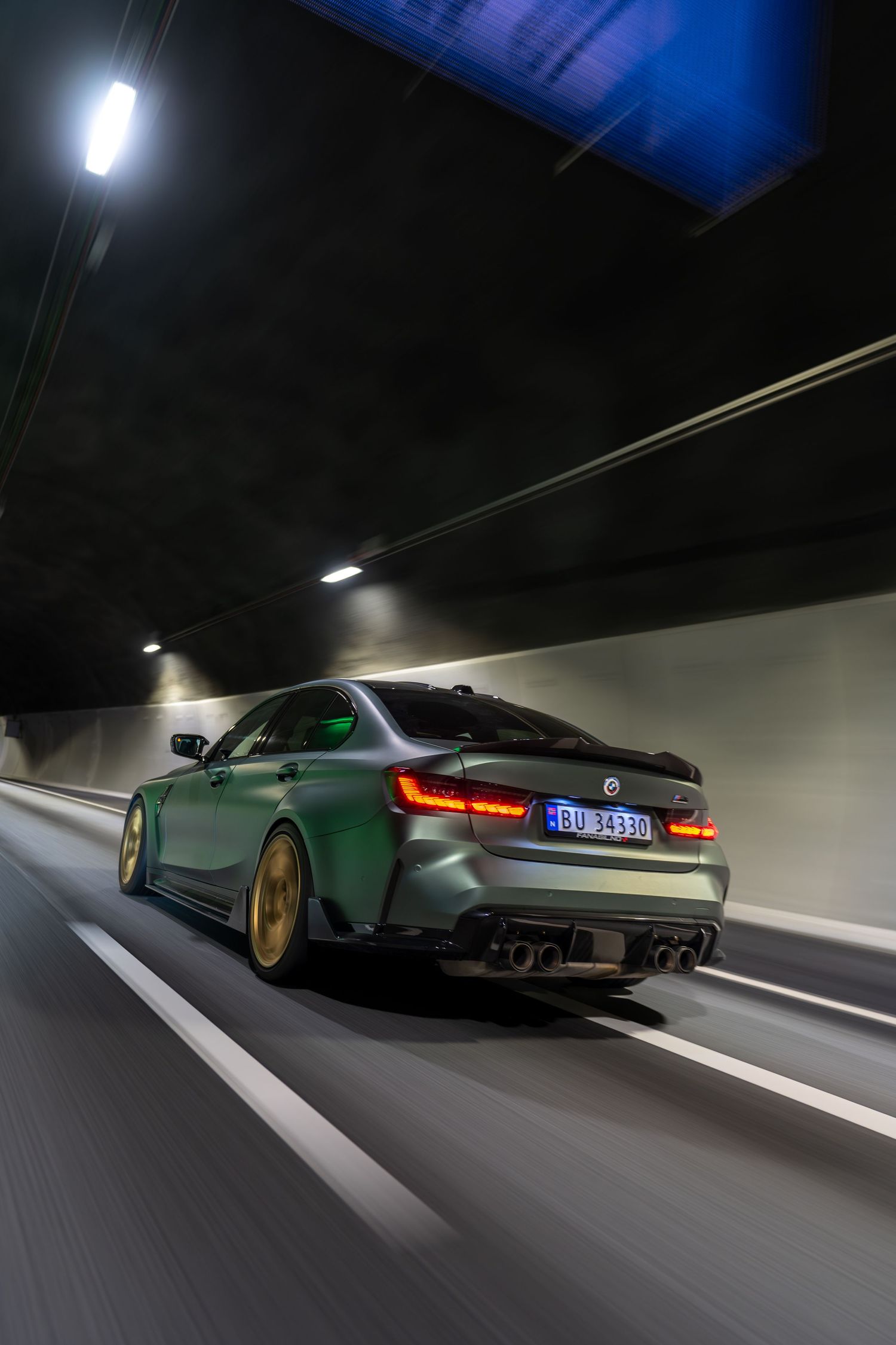 BMW M3 with gold wheels captured in dynamic tunnel shot showing motion blur.