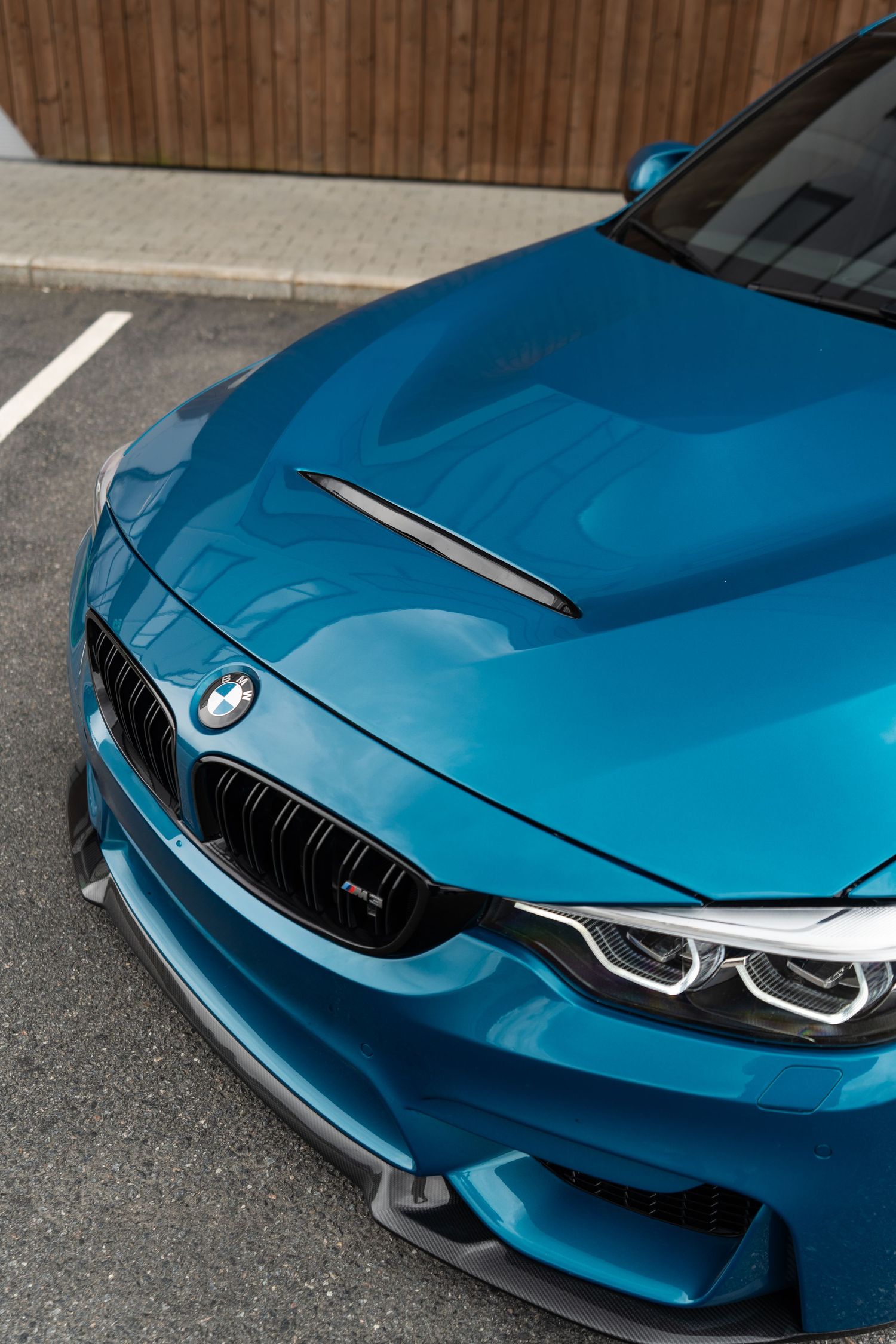 Close-up view of a bright blue BMW M4's front end showing the signature kidney grilles and aggressive bodywork details.