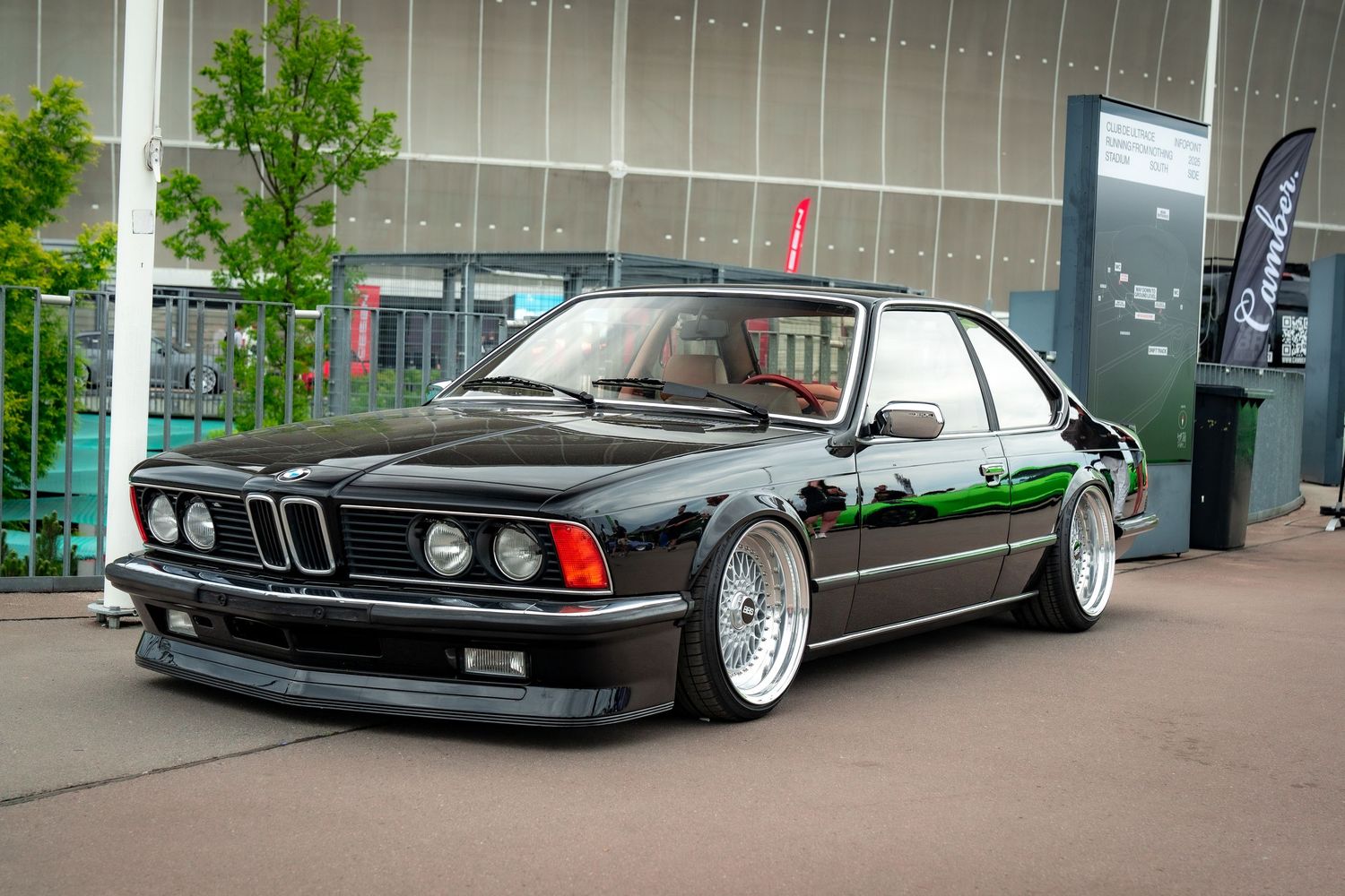 Classic black BMW E24 6-series lowered on silver multi-spoke wheels.