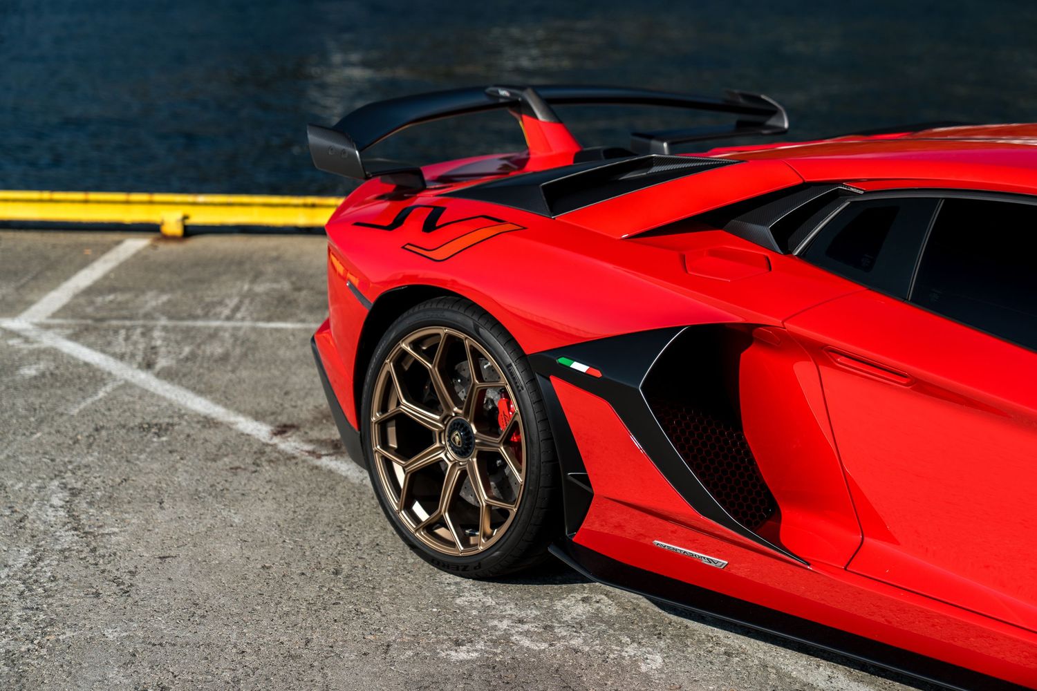 Close-up view of a red Lamborghini Aventador's front wheel and aggressive side bodywork details.