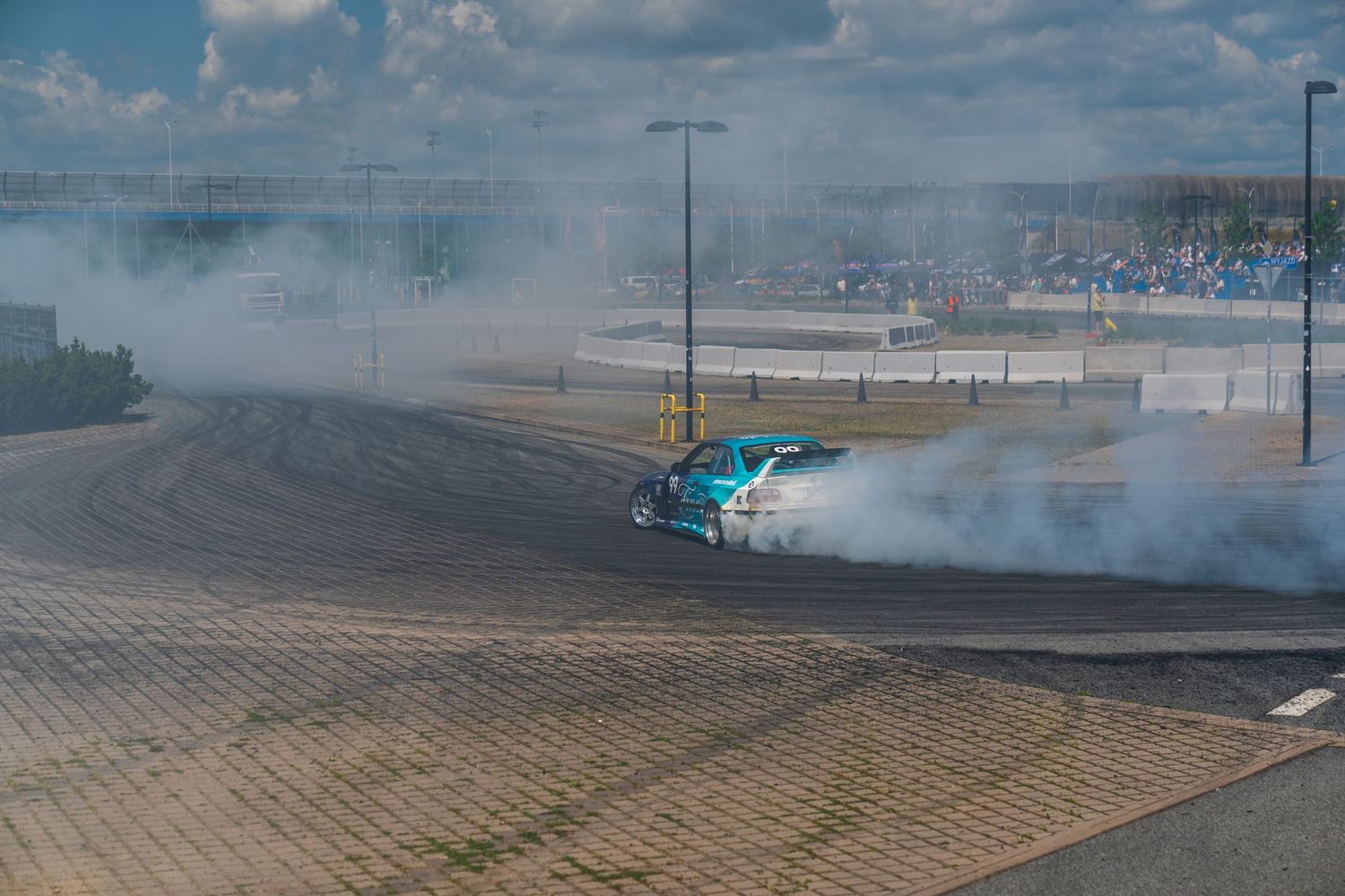 Drifting car creating smoke during a performance at an outdoor track.