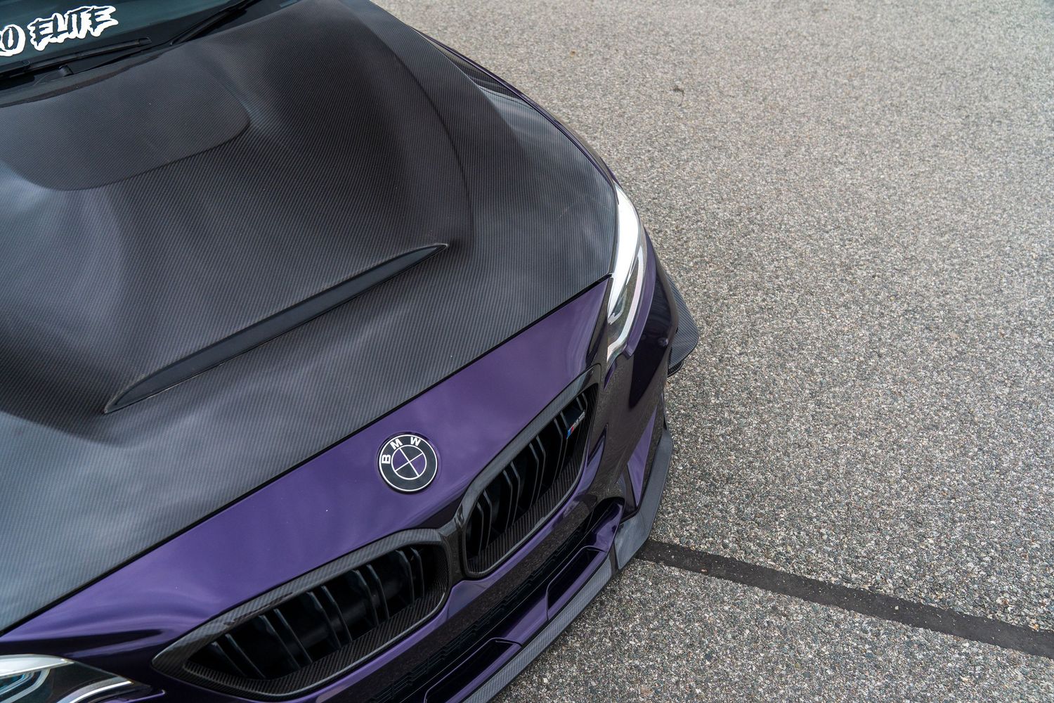 Close-up view of a BMW M-series car hood with purple metallic paint accents.