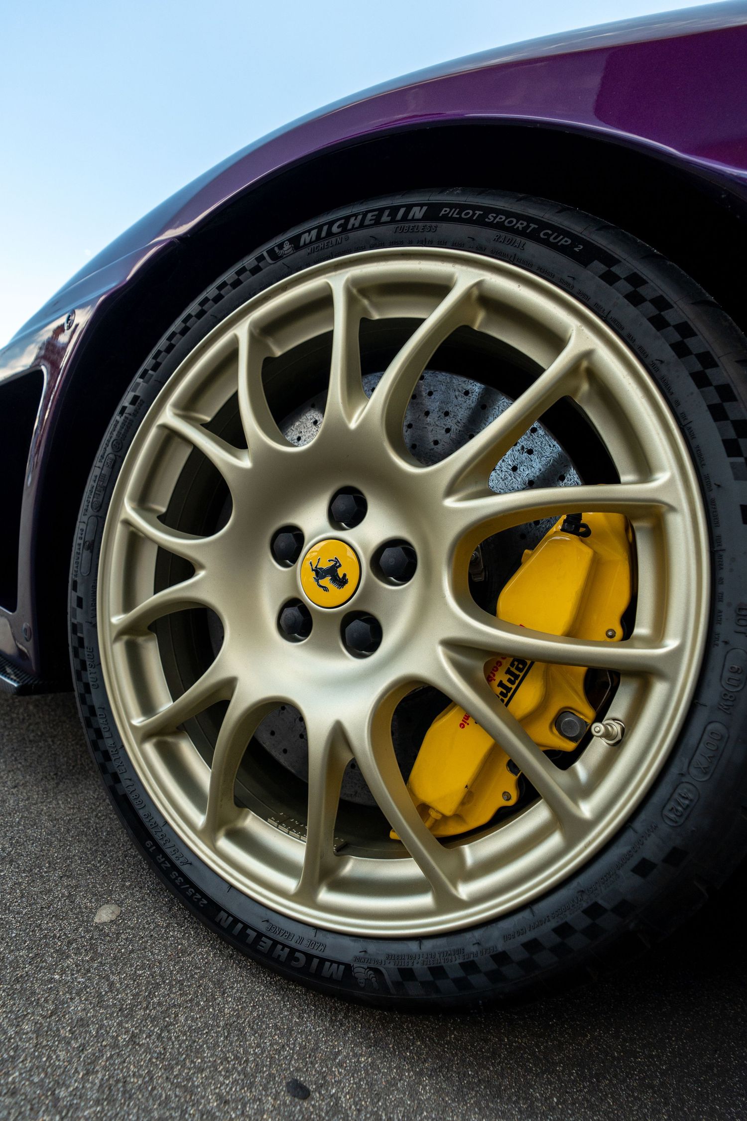 Gold Ferrari wheels with yellow brake calipers showcasing high-performance braking system.