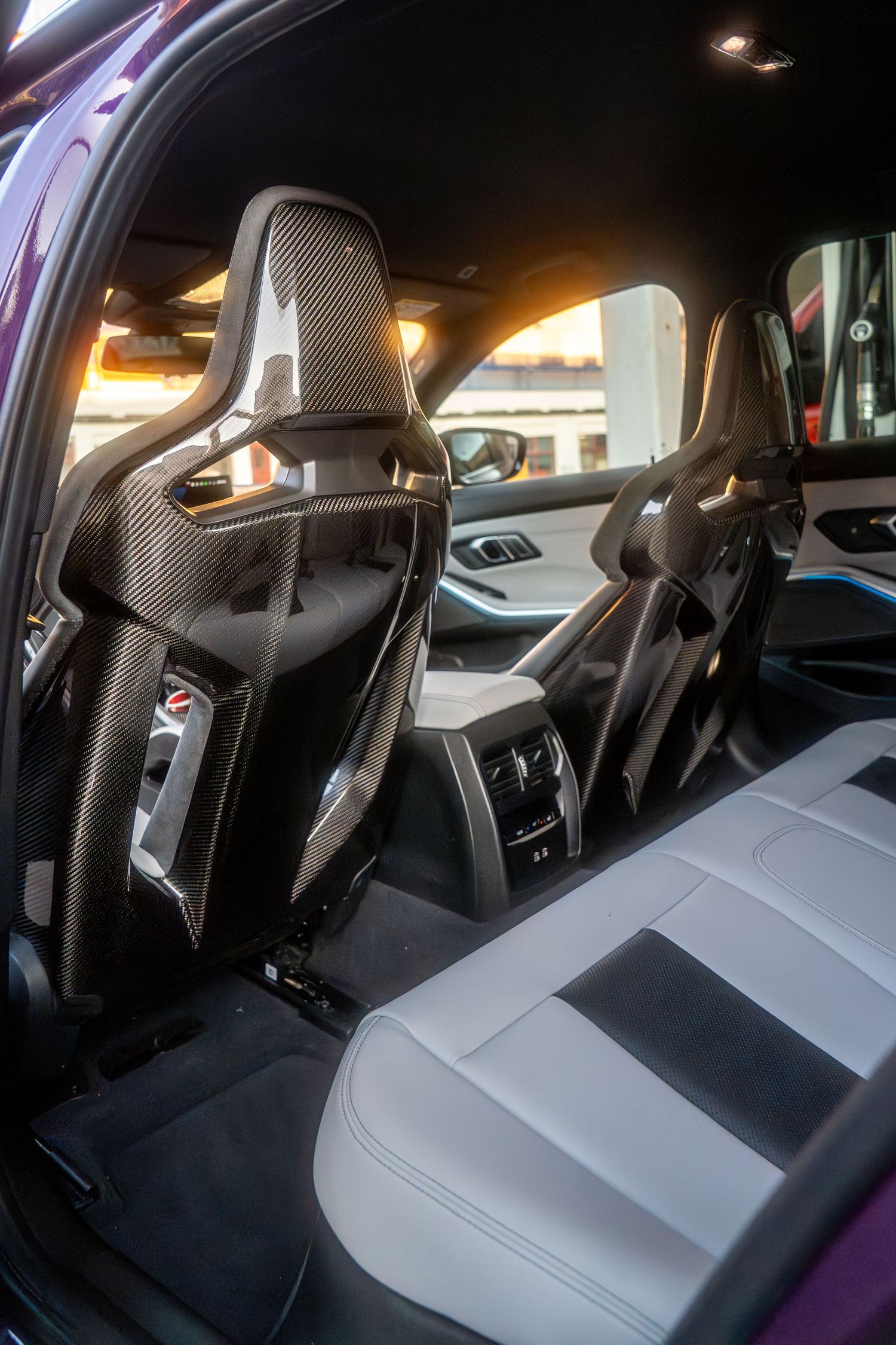 Interior view of modern sports car showing performance seats with carbon fiber backs and ambient lighting.