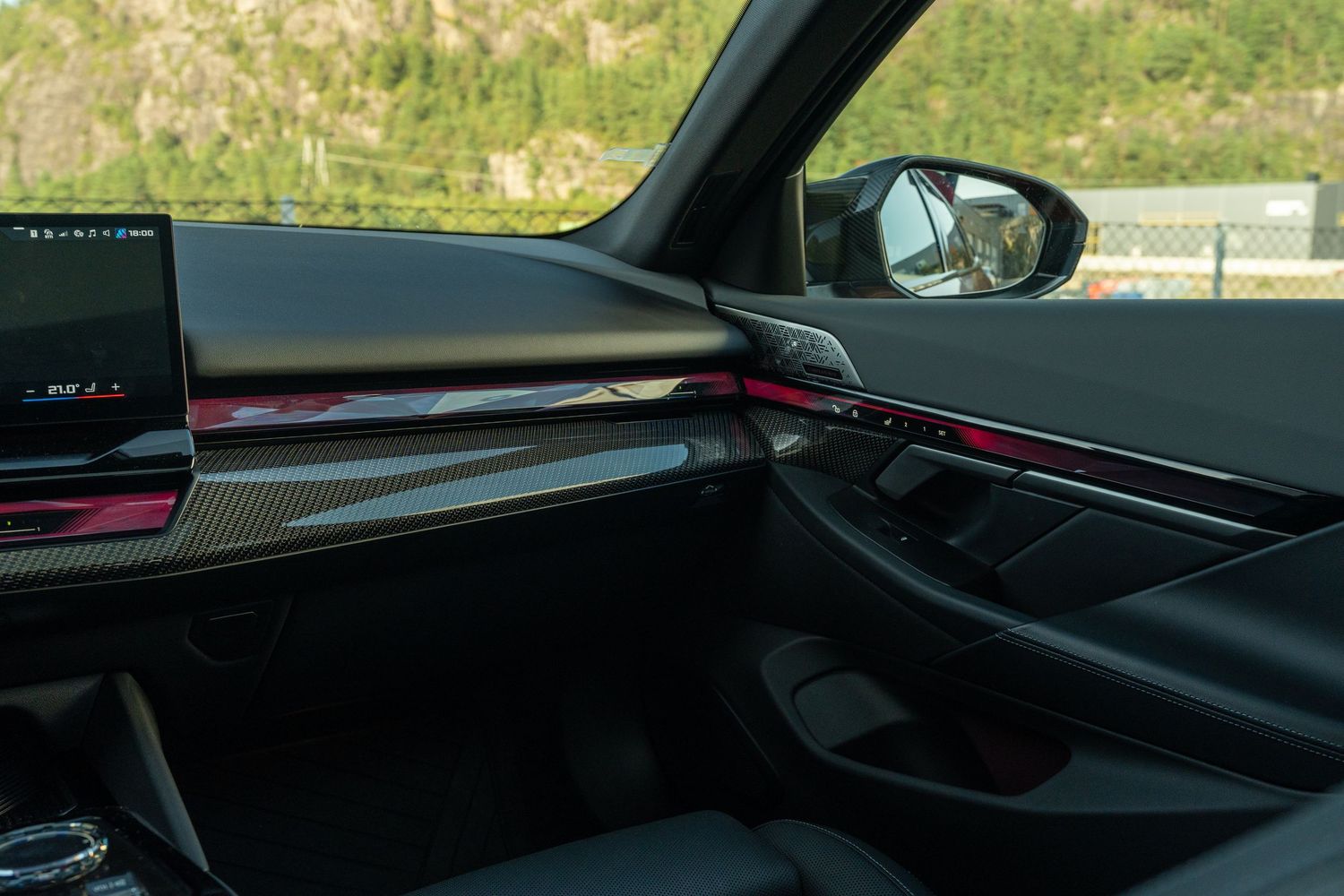 Modern car dashboard interior showing sleek design elements and side view mirror through window.