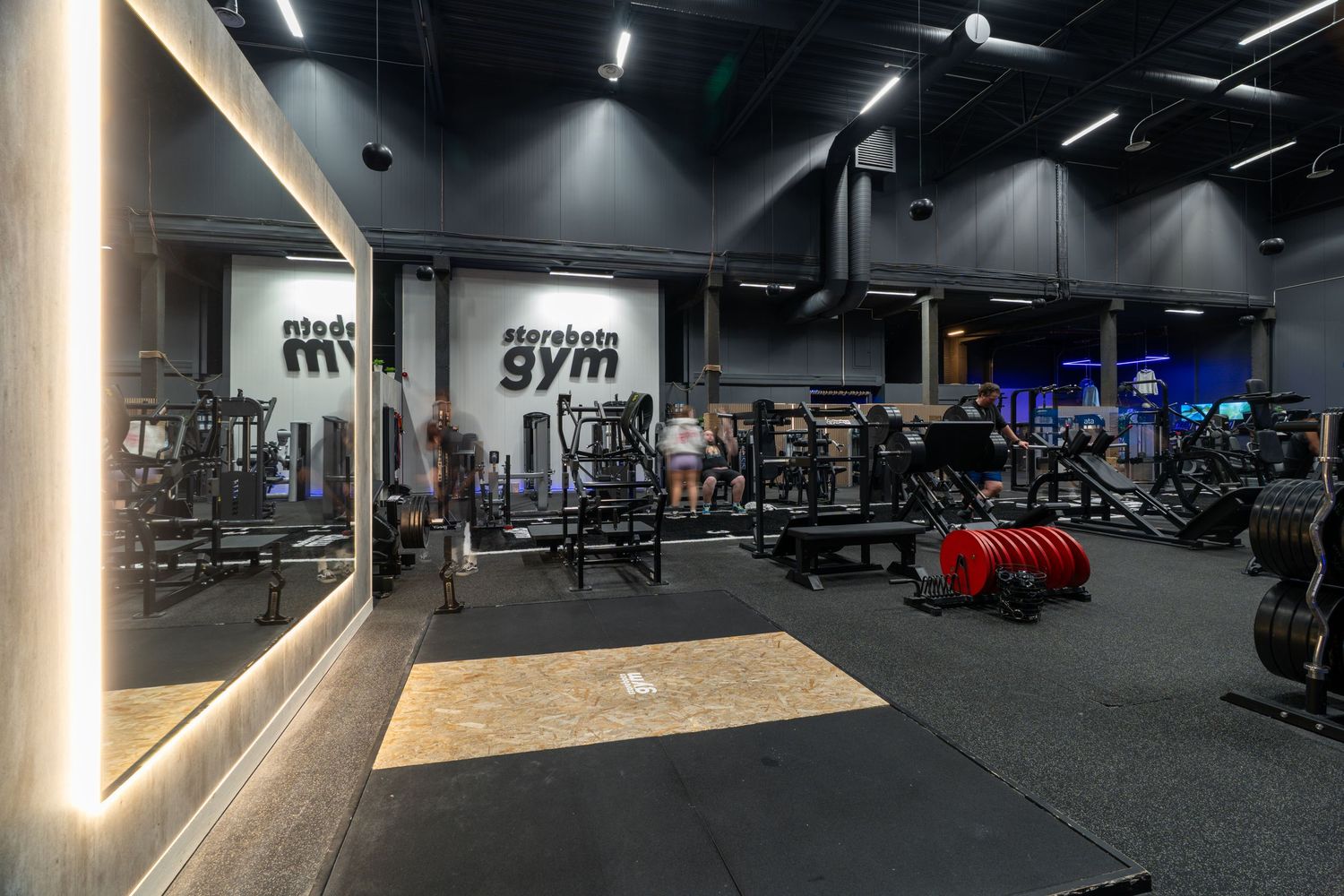 Modern gym interior with weight equipment and LED lighting in dark atmospheric setting.